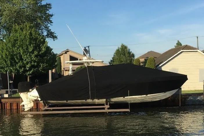 Covered 1994 Intrepid 30 Open Cuddy boat docked by waterfront homes.