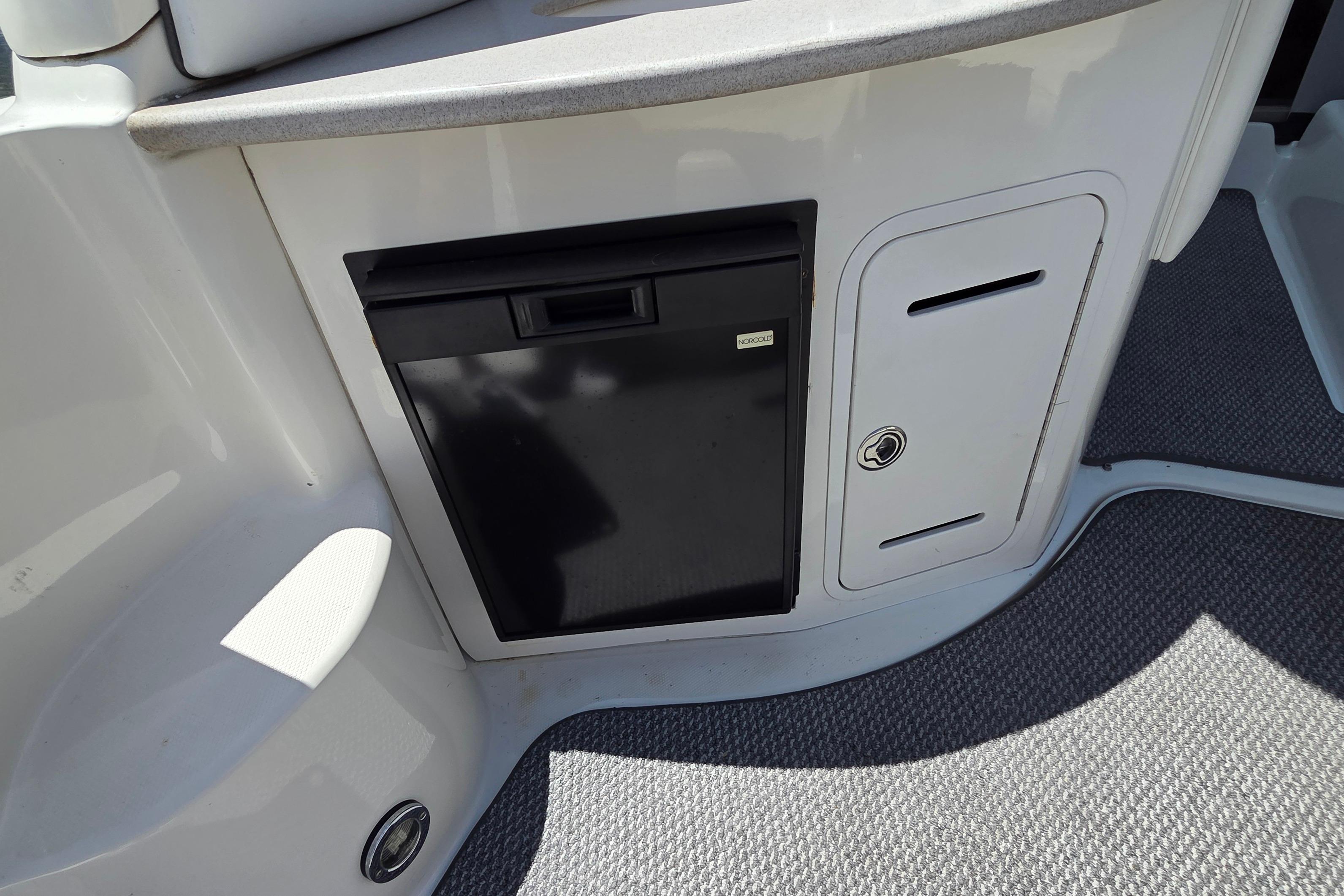 2006 Sea Ray Sundancer 320 interior with compact fridge and storage compartment.