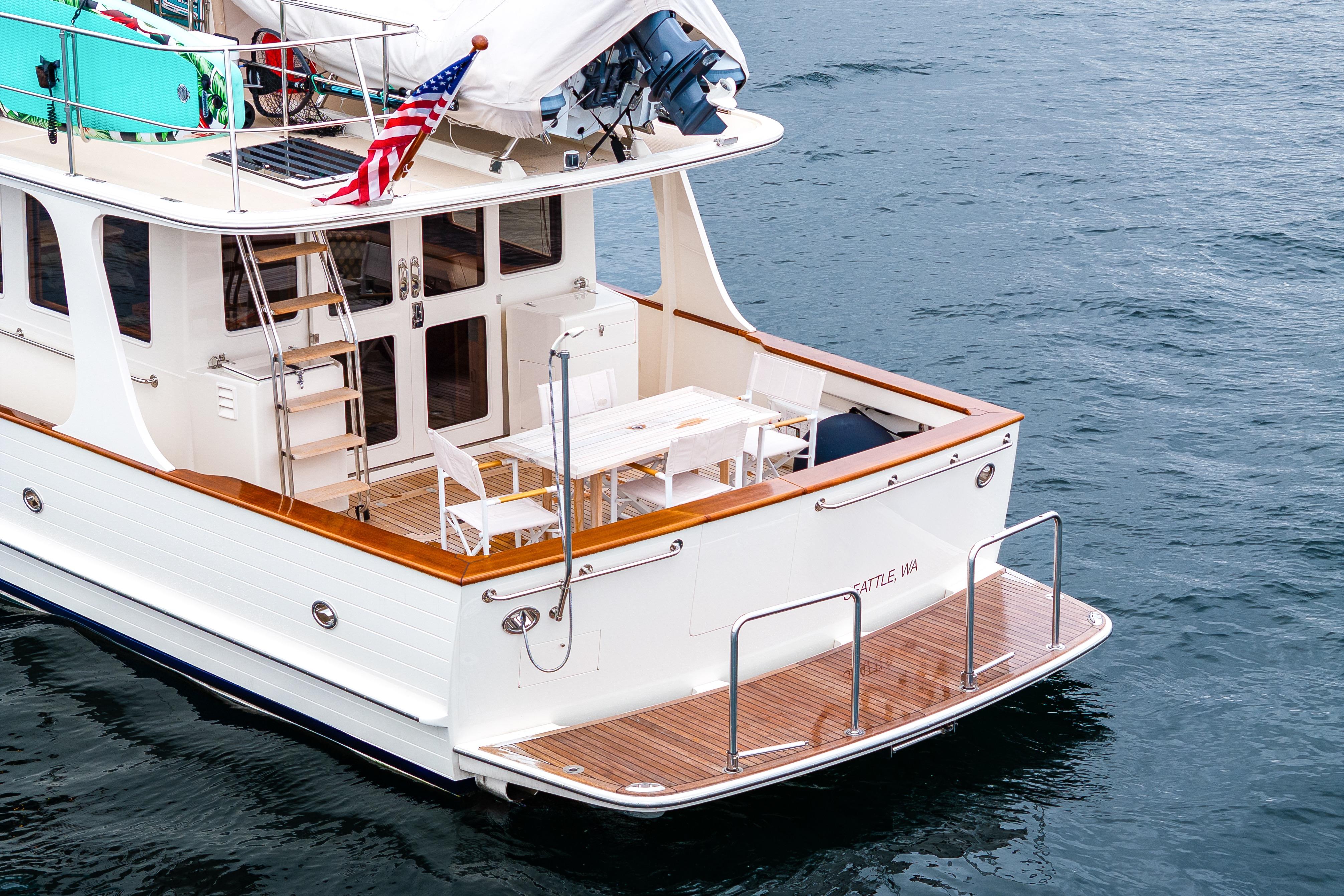 2026 Fleming 55 Pilothouse yacht with deck seating, docked on calm water.