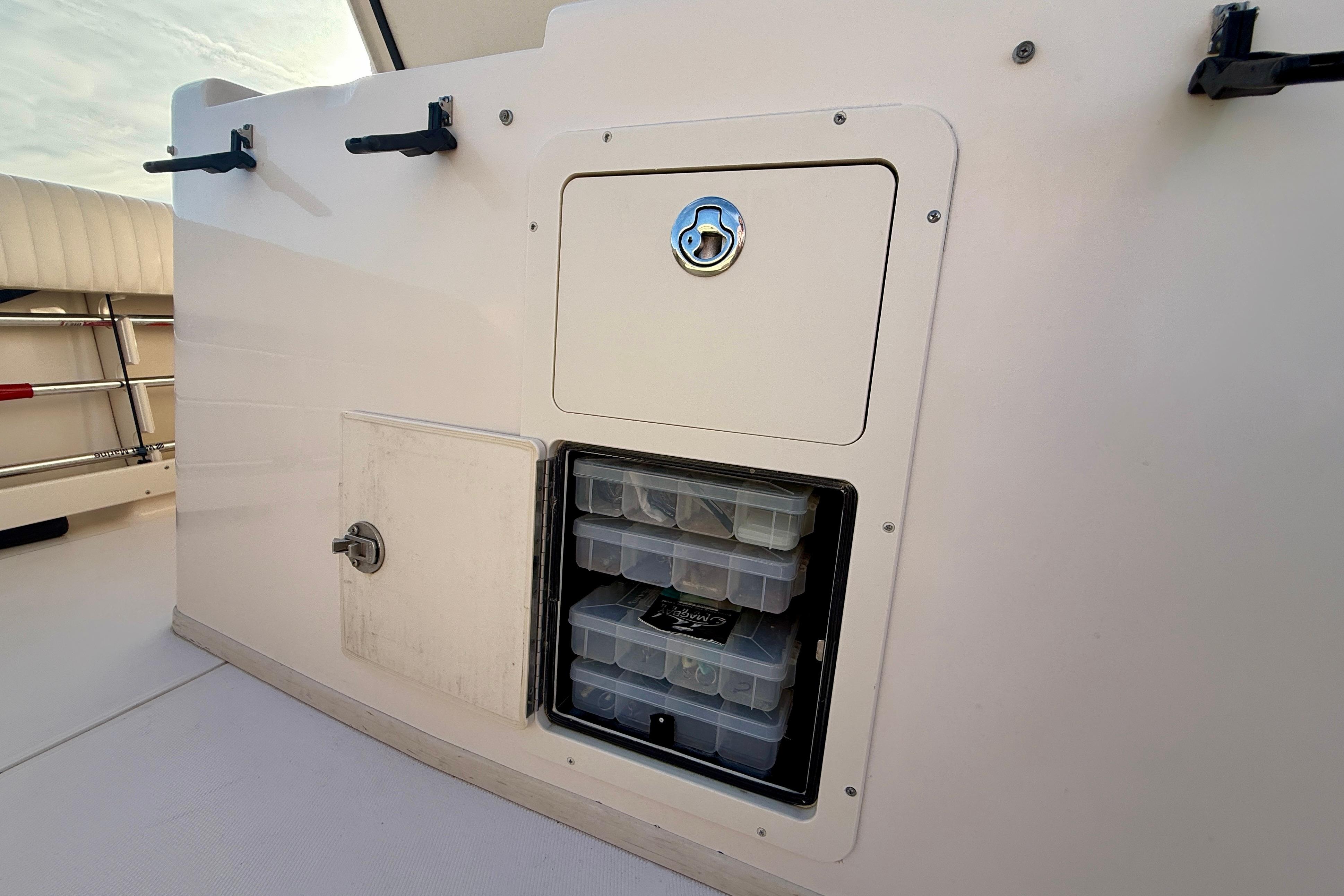 Storage compartment on a 2012 Grady-White Canyon 336 boat, featuring organized tackle boxes.