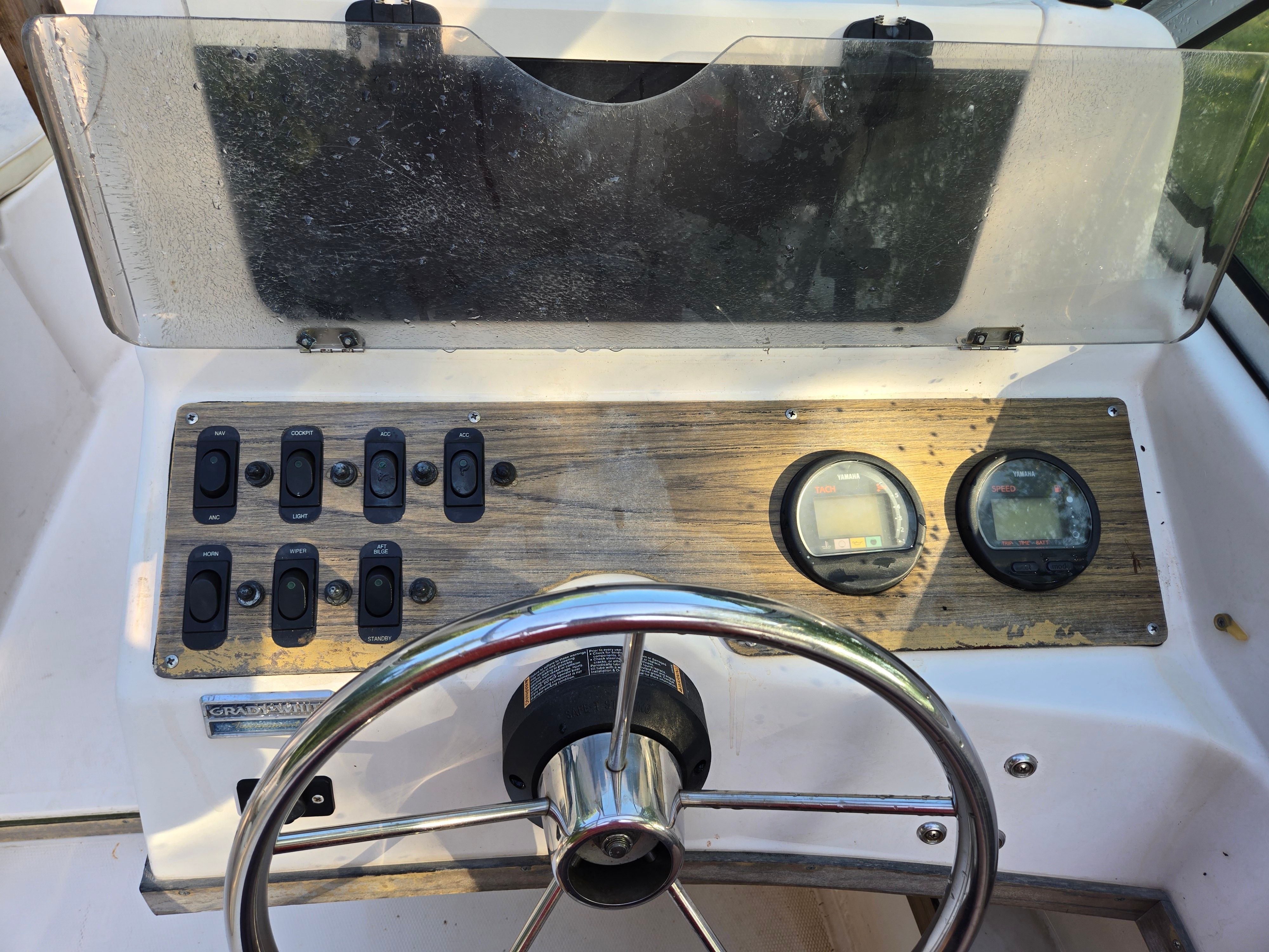 The image shows a boat's helm with a steering wheel and instruments.