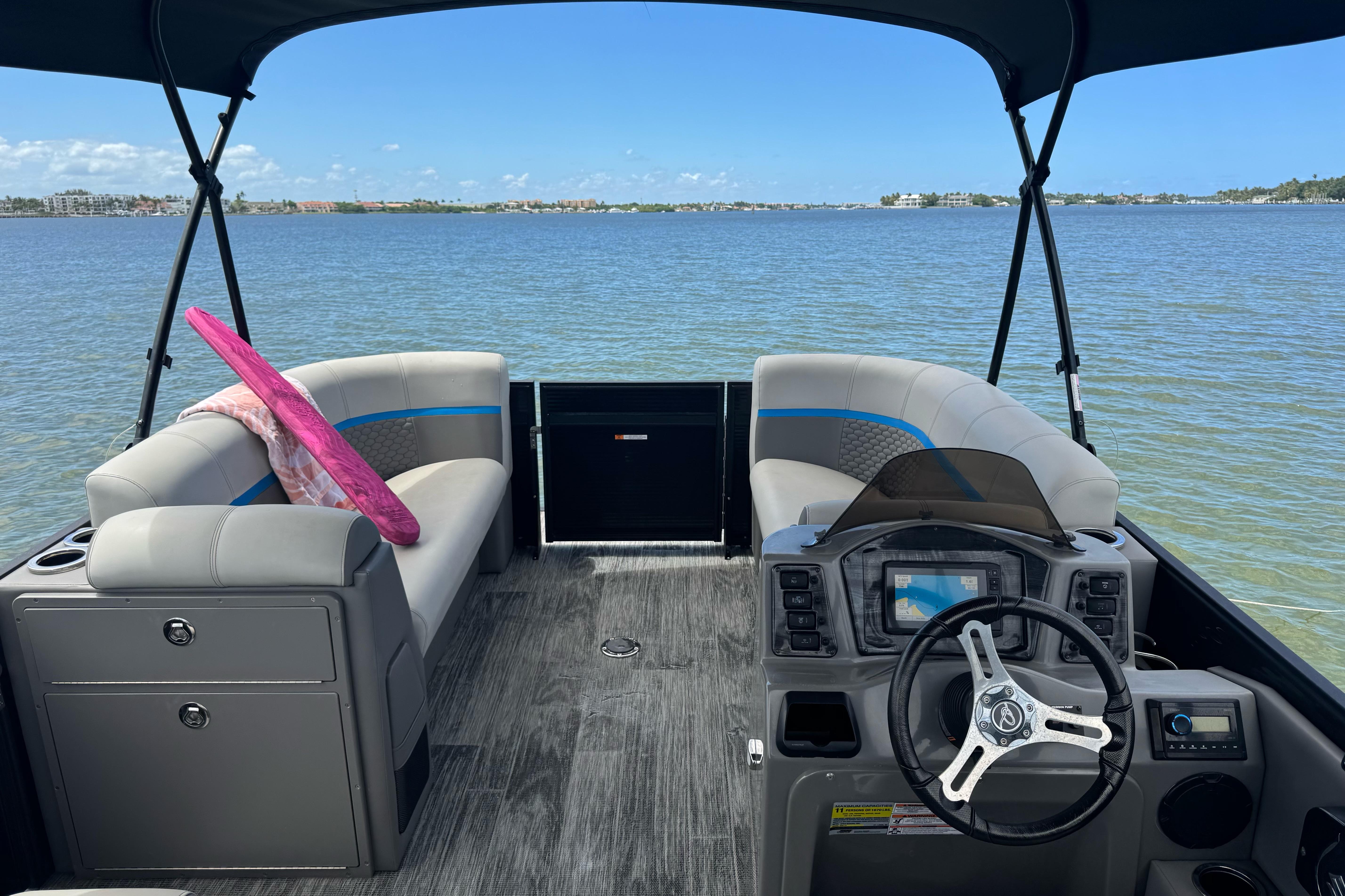 Pontoon boat interior with seating and steering, Qwest Edge 820 CTR, 2022 model, on calm water.
