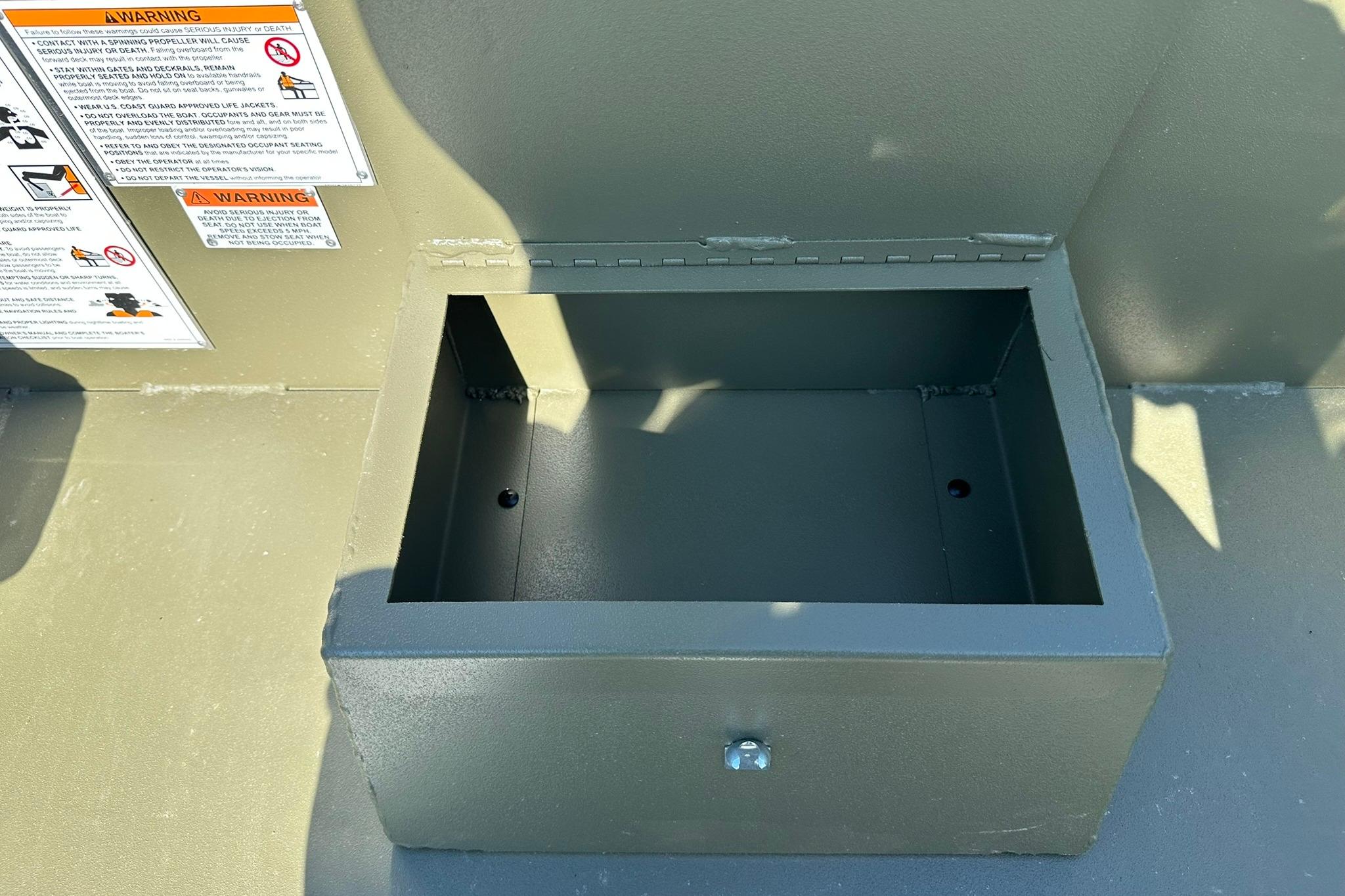 Open storage compartment on 2026 Lowe Roughneck 1860SC boat with warning labels.