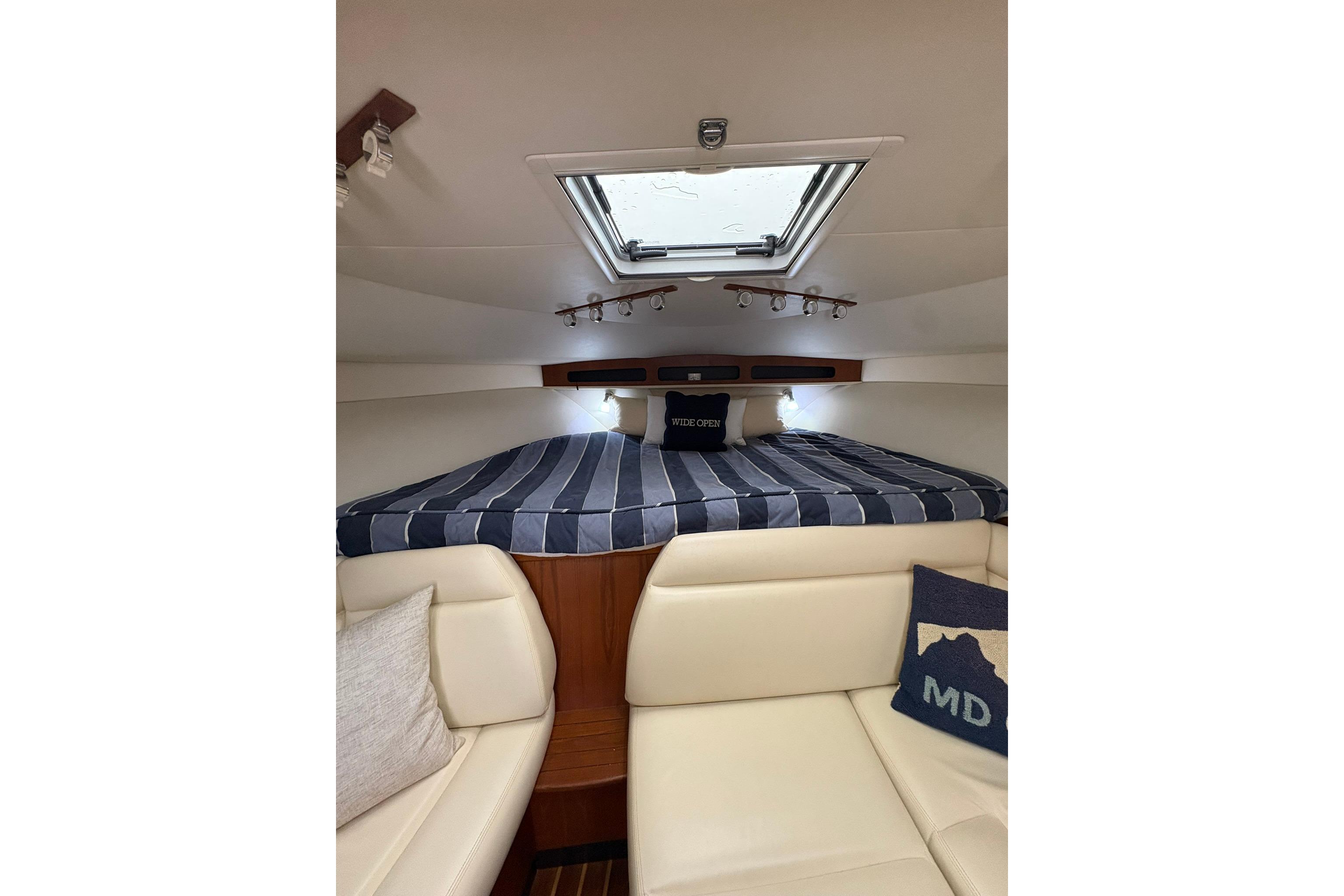2008 Tiara Yachts 3000 Open cabin interior with striped bedding and skylight.
