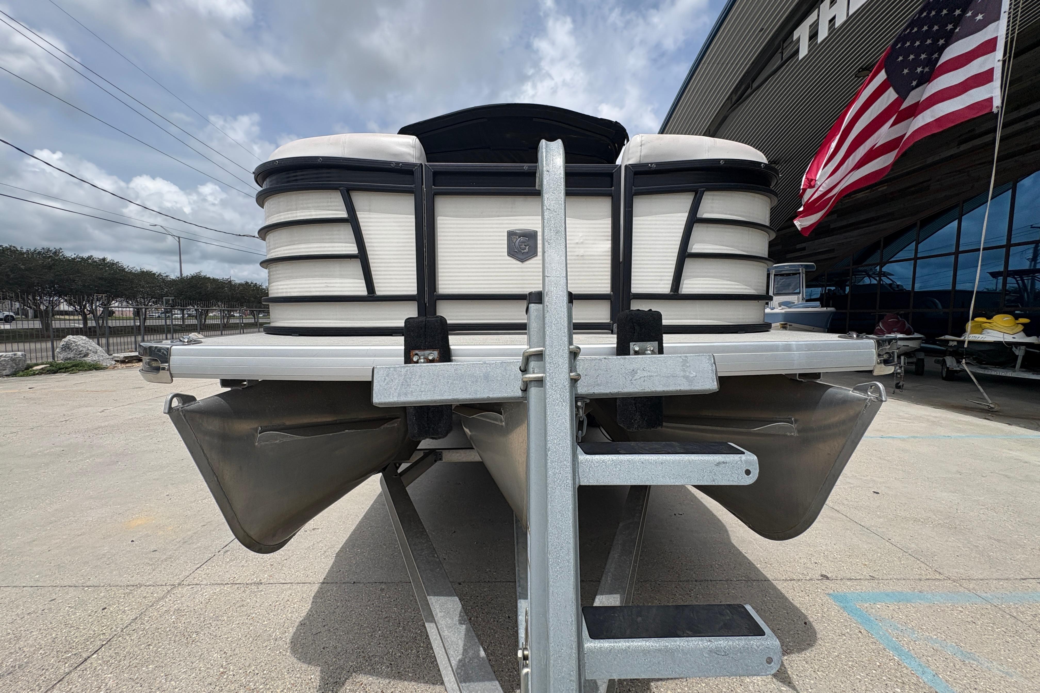 2019 Godfrey Aqua Patio pontoon boat on trailer, American flag in background.