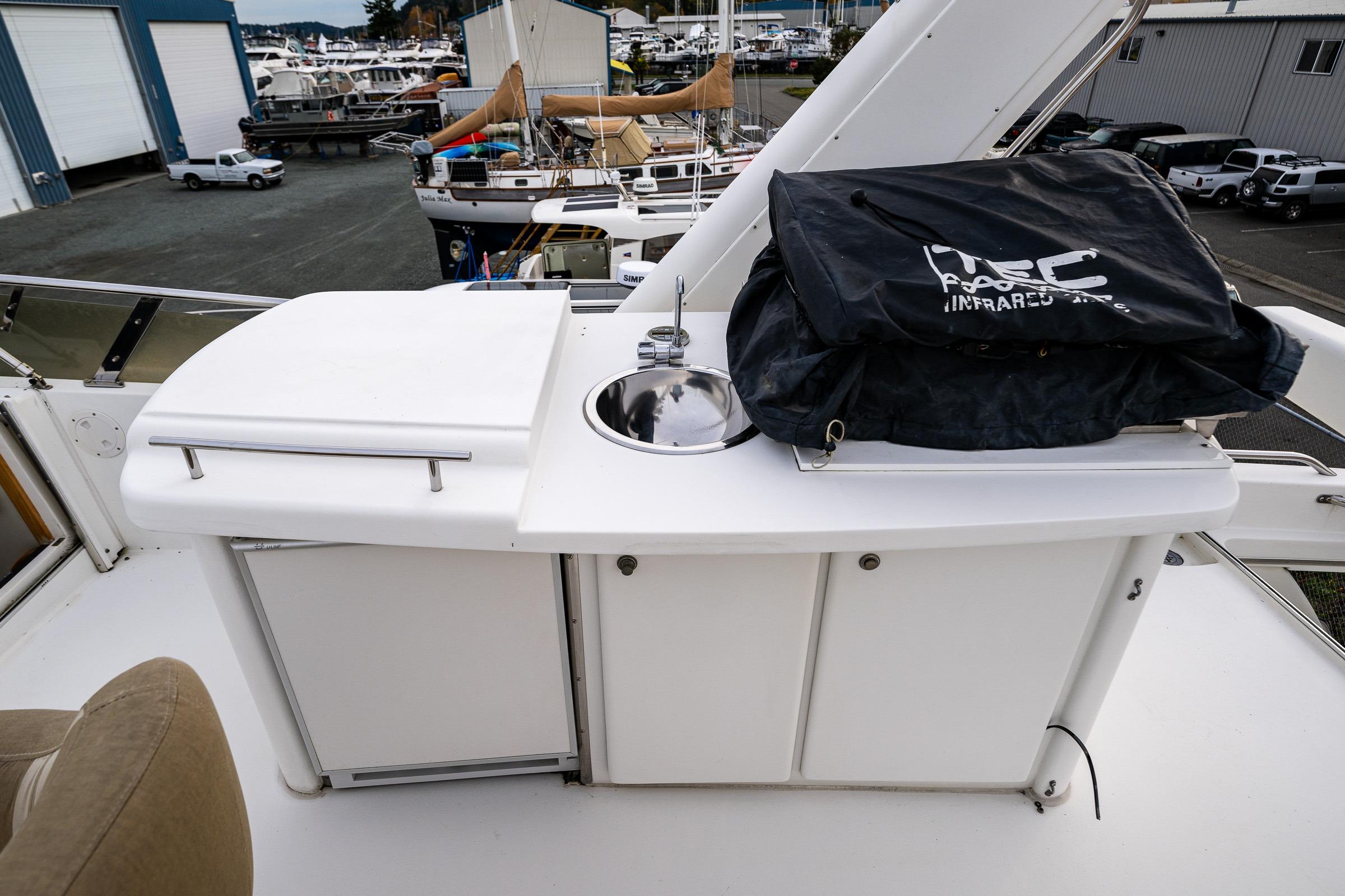 Outdoor kitchen area on 2001 Navigator Pilothouse yacht with sink and storage.