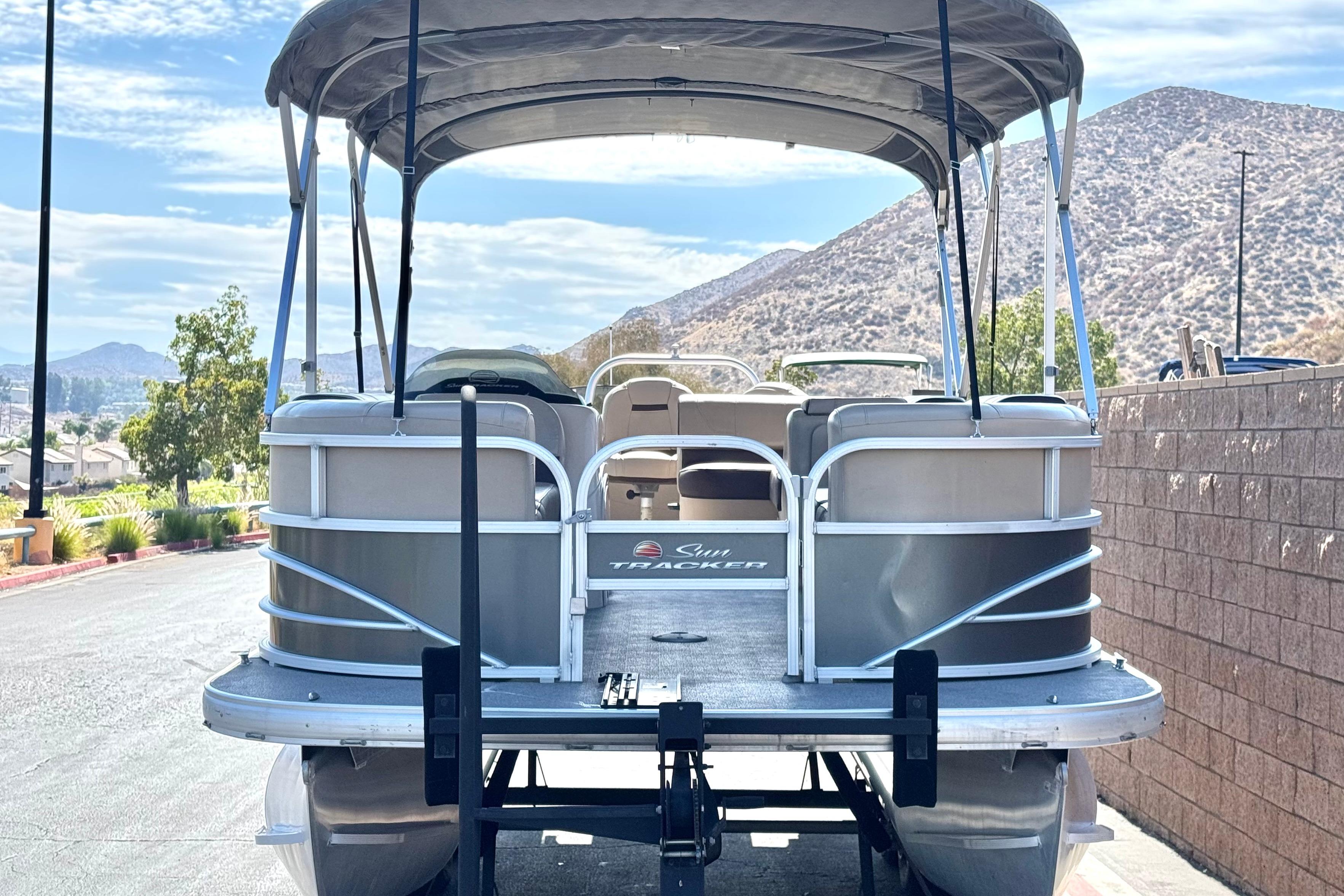 2018 Sun Tracker SportFish 22 DLX pontoon boat parked with scenic mountain backdrop.