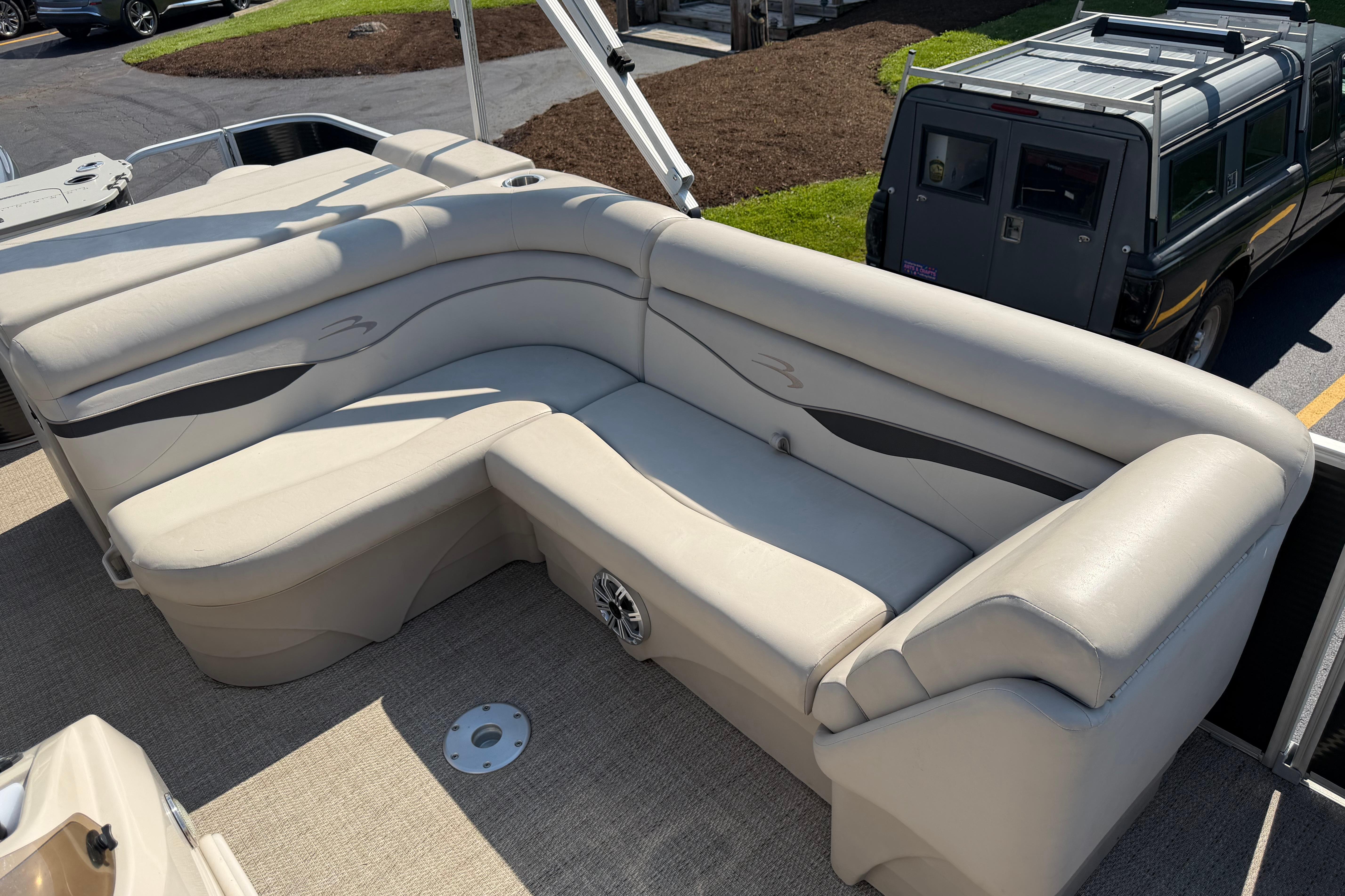 2018 Bennington 21 SF boat with beige seating and speaker, parked near a vehicle.