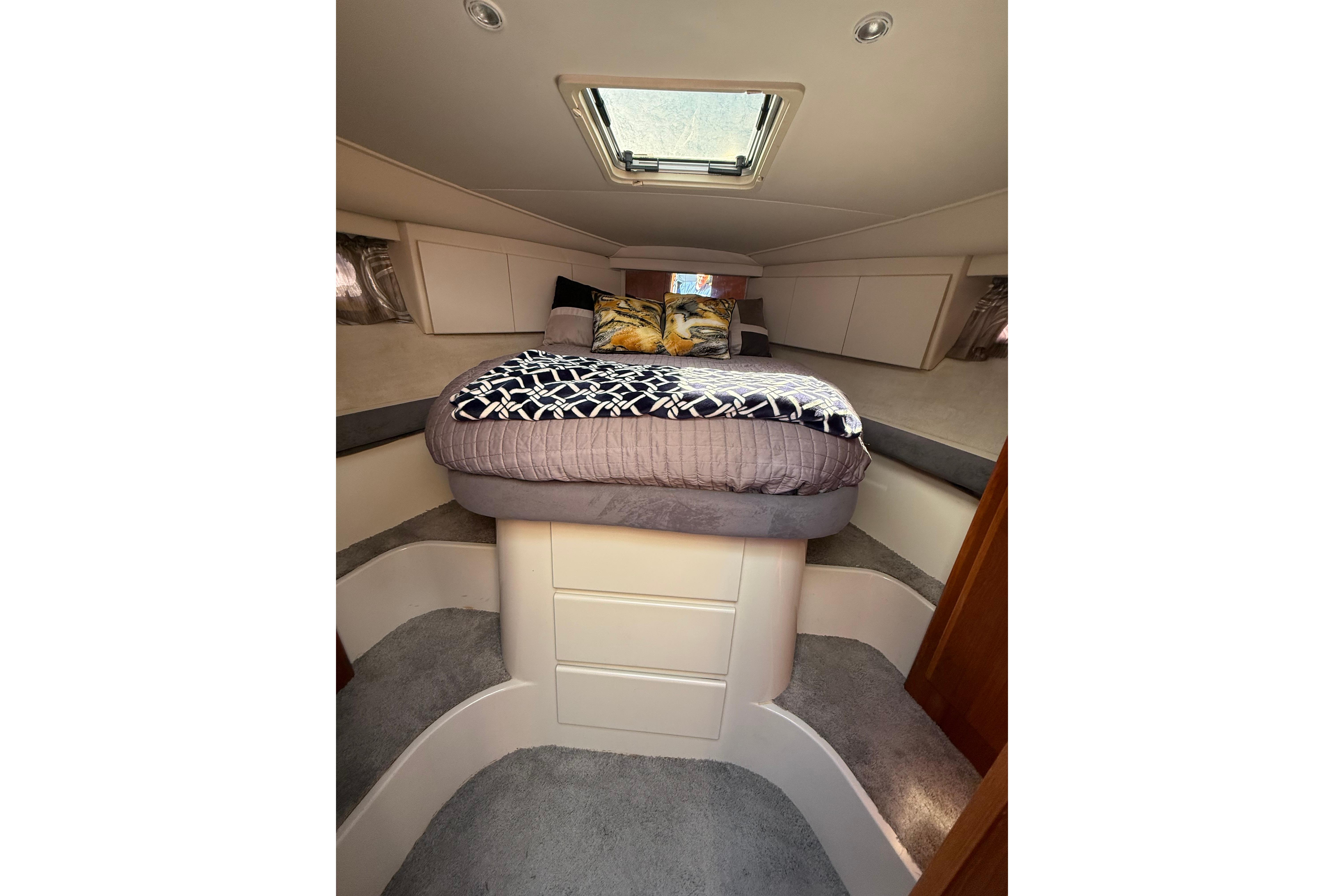 Cozy cabin interior of 1995 Carver 370 Voyager yacht with skylight and plush bedding.
