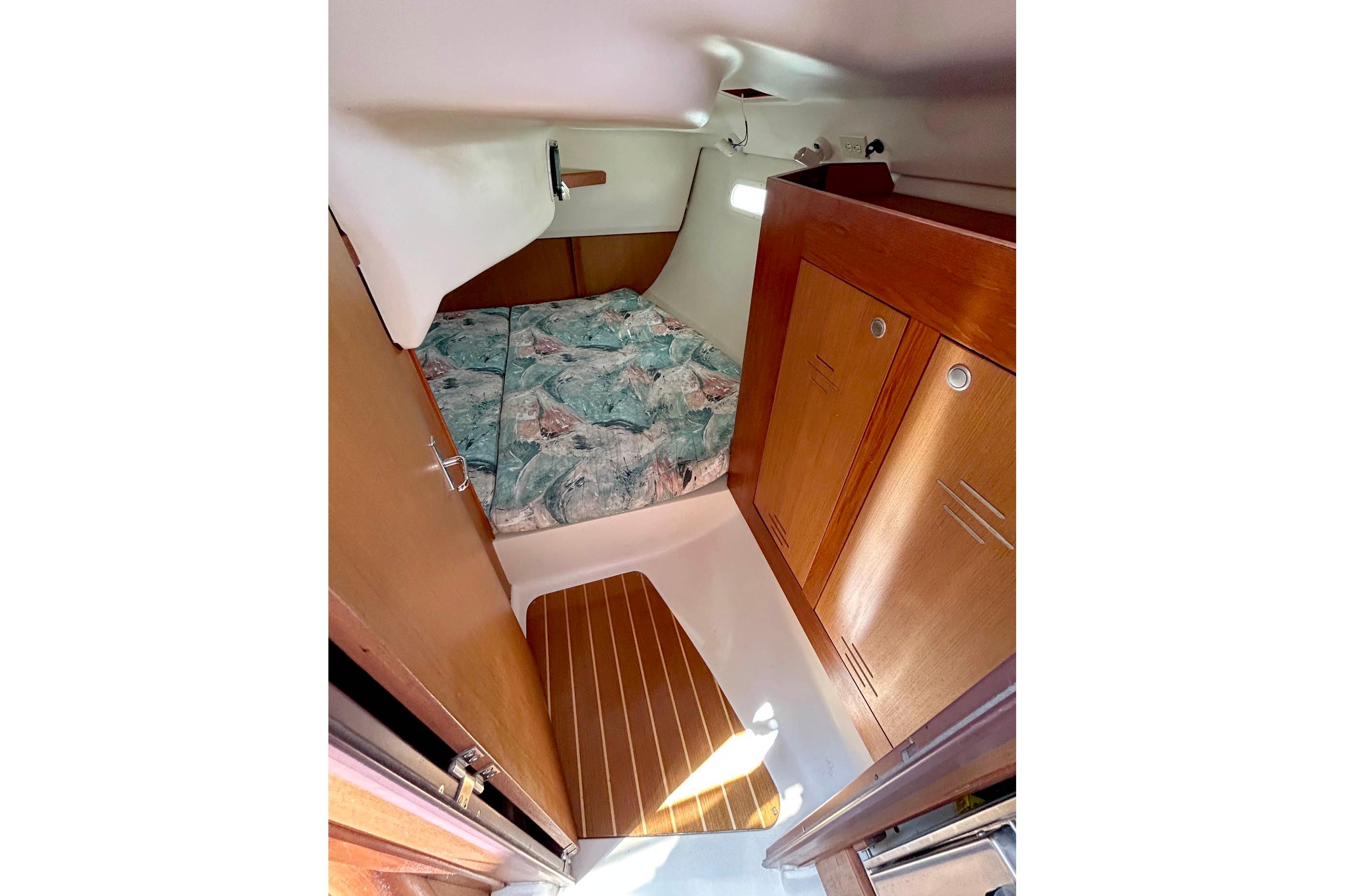 Interior cabin of 1998 Hunter 340 sailboat with bed and wooden storage cabinets.