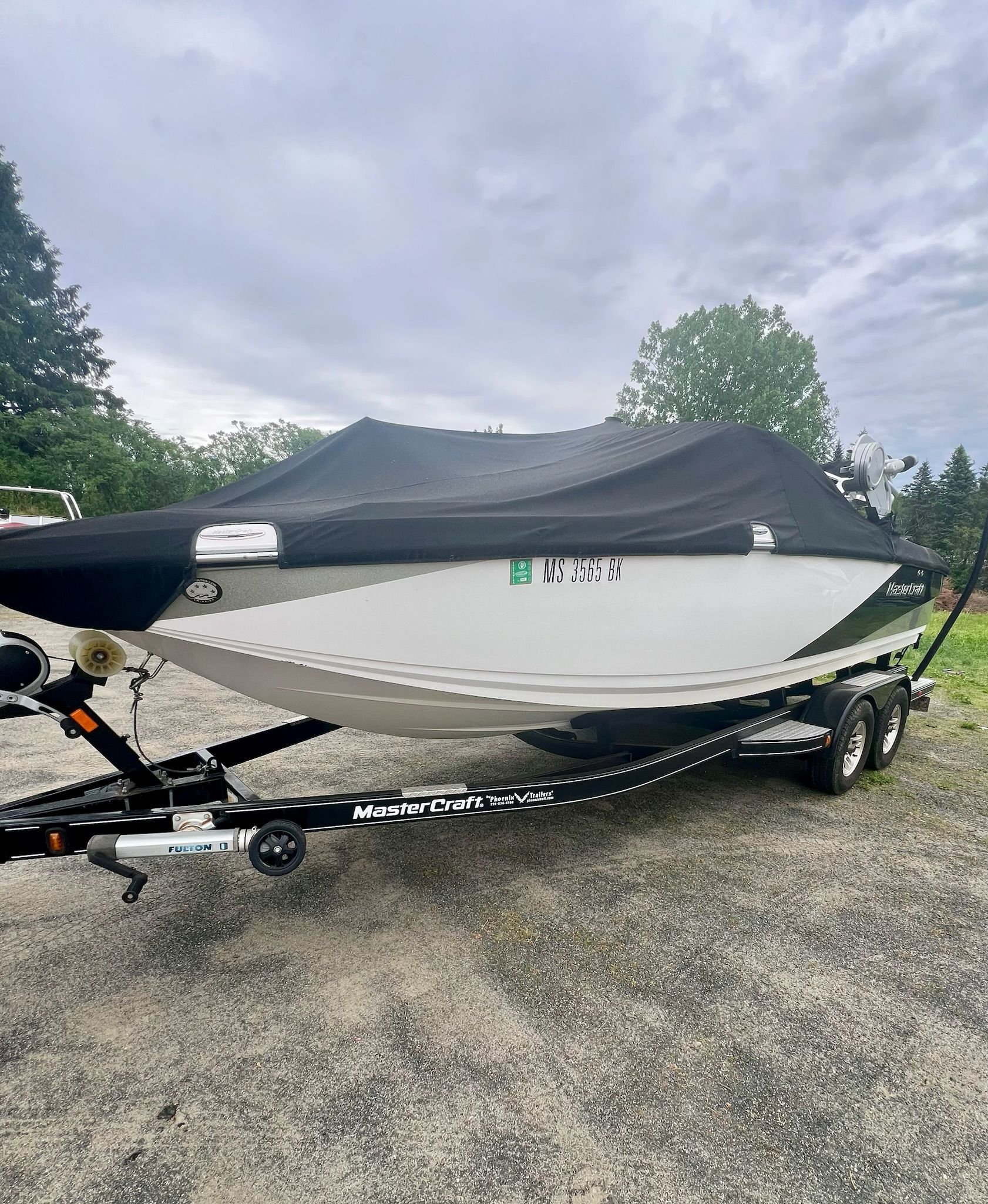 A 2013 MasterCraft X-25 boat on a trailer, covered with a black tarp.