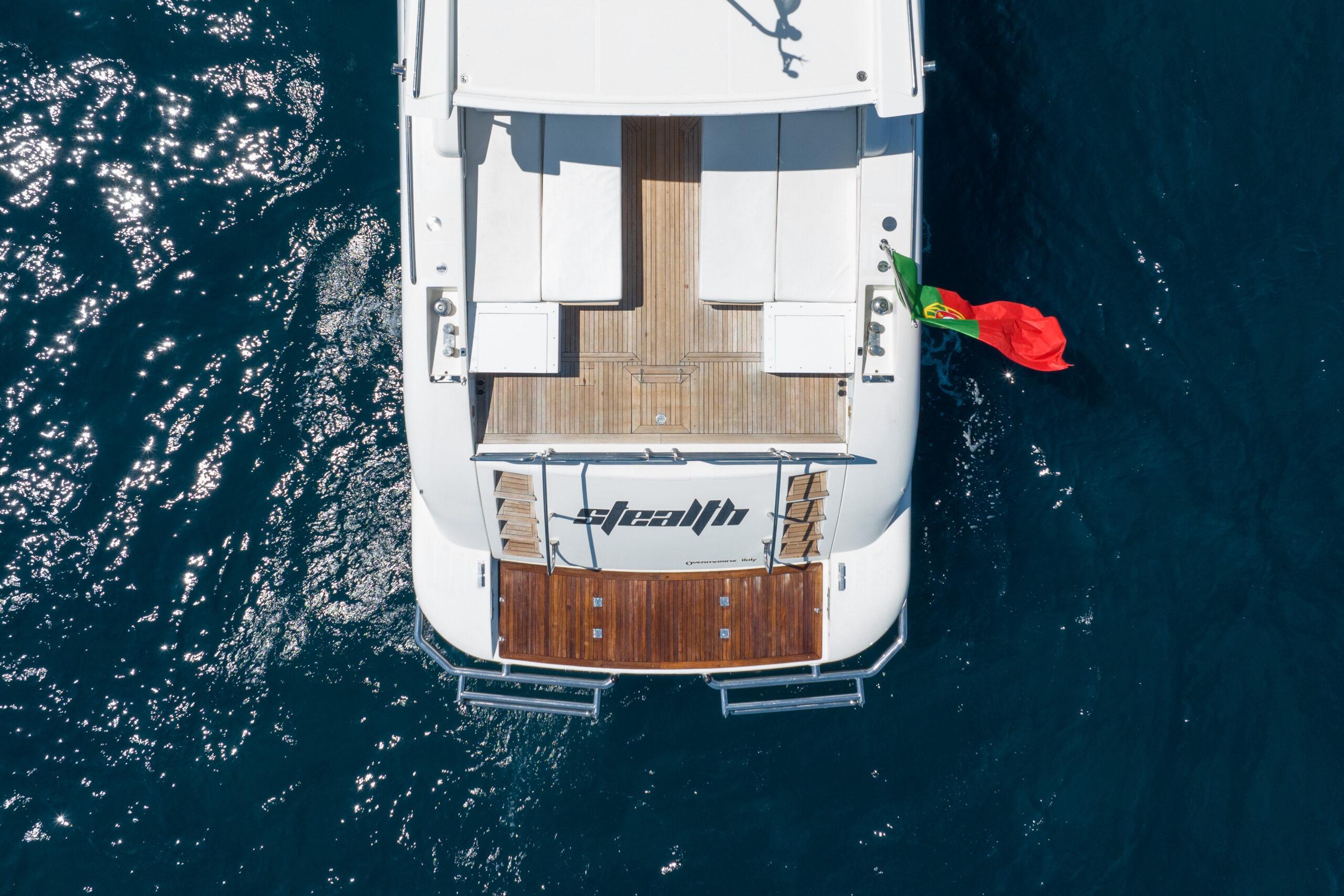 Aerial view of 2006 Mangusta 80 yacht with Portuguese flag on blue ocean.