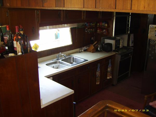 1980 Pluckebaum Baymaster kitchen with wooden cabinets, double sink, and appliances.