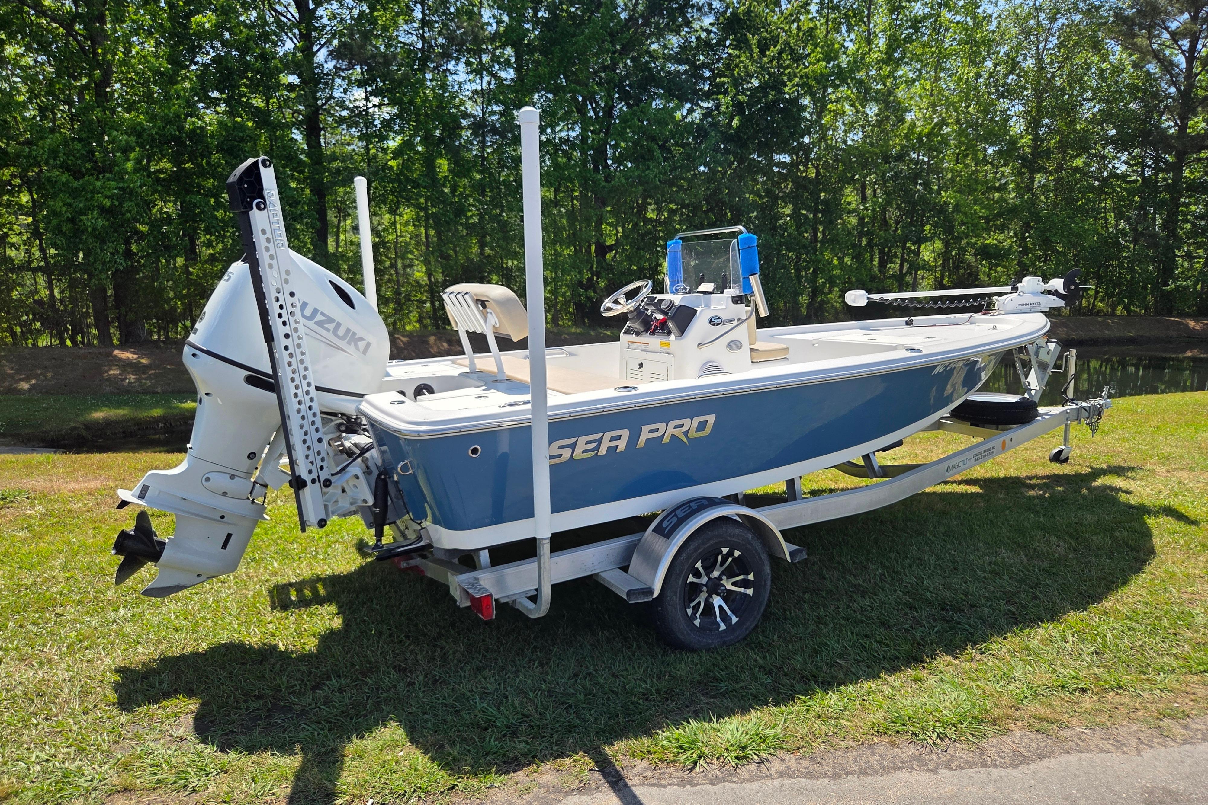 2024 Sea Pro 172 Bay boat with Suzuki engine on trailer, parked on grass.
