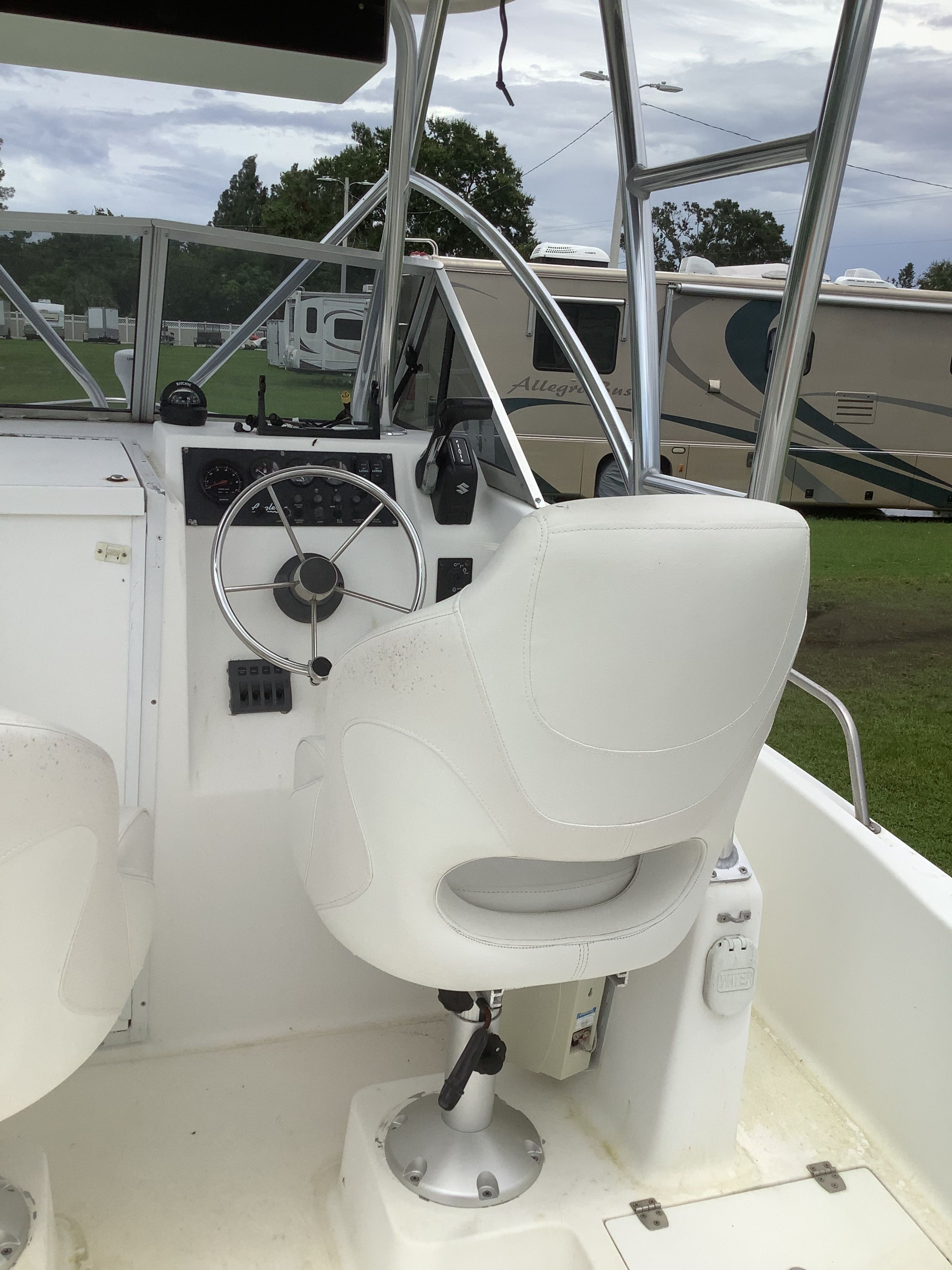 The cockpit of a boat with white seats and a steering wheel.