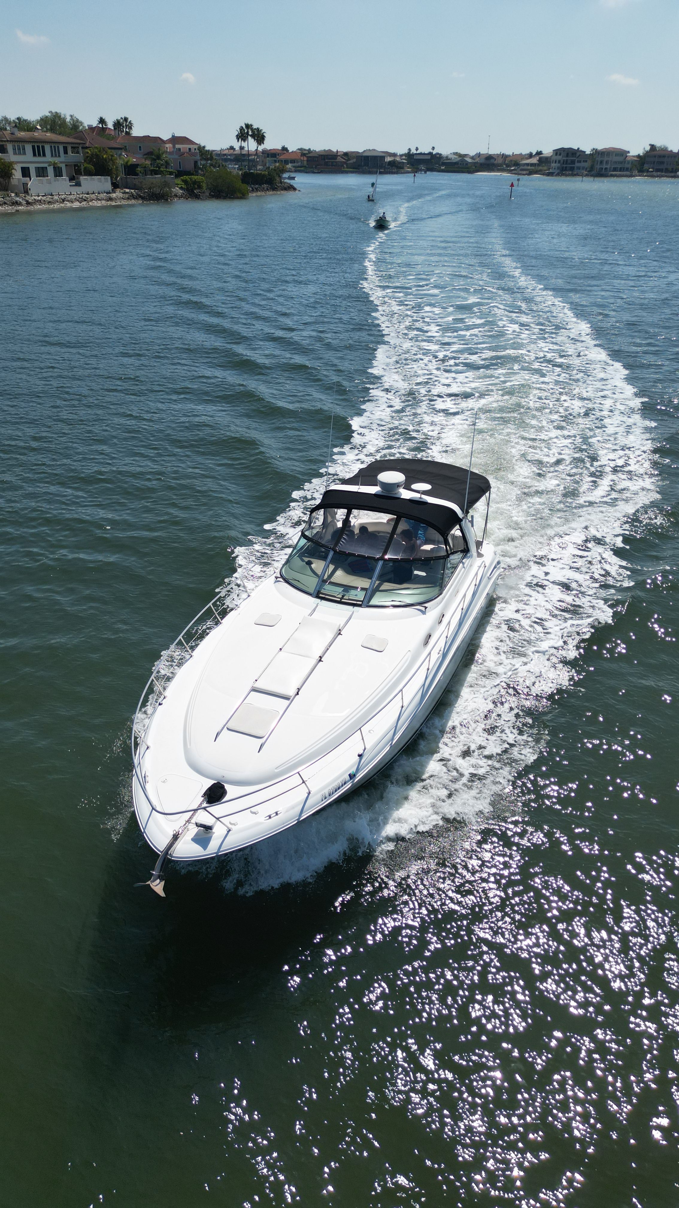 A white motorboat cruises on calm waters, surrounded by coastal houses.