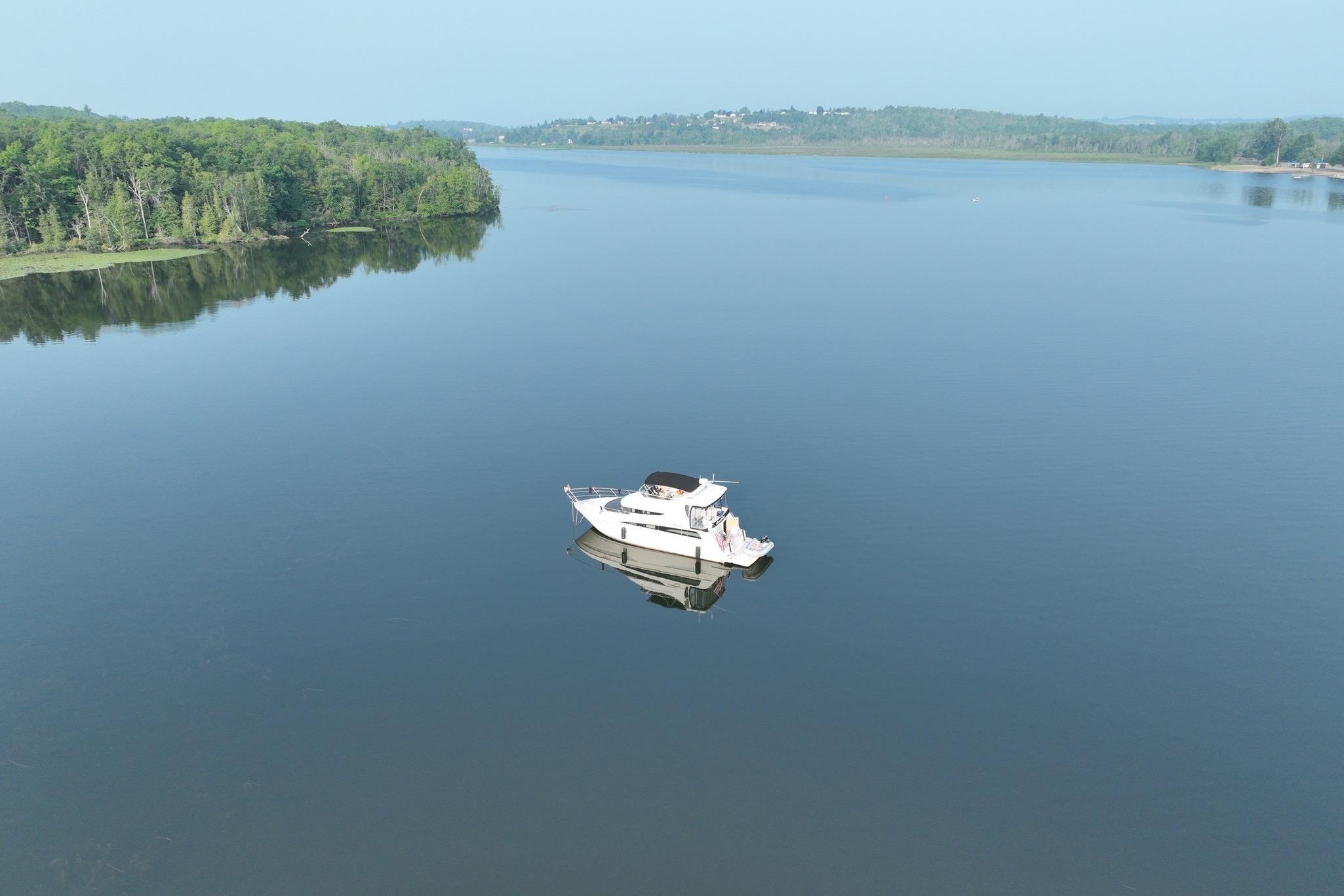 2006 Carver 43 Motor Yacht on serene lake with lush green shoreline.