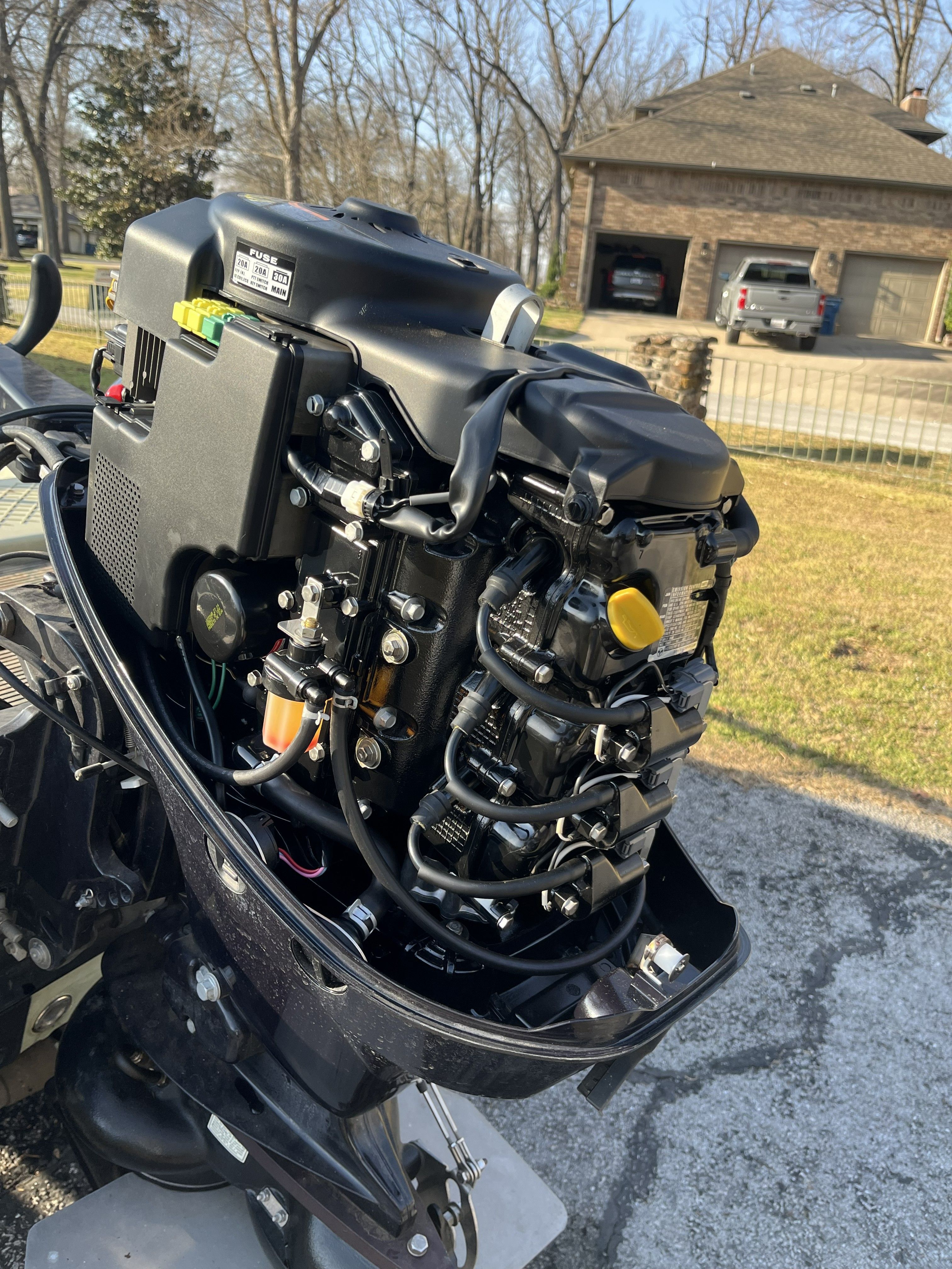 An outboard motor on a boat, with a house in the background.