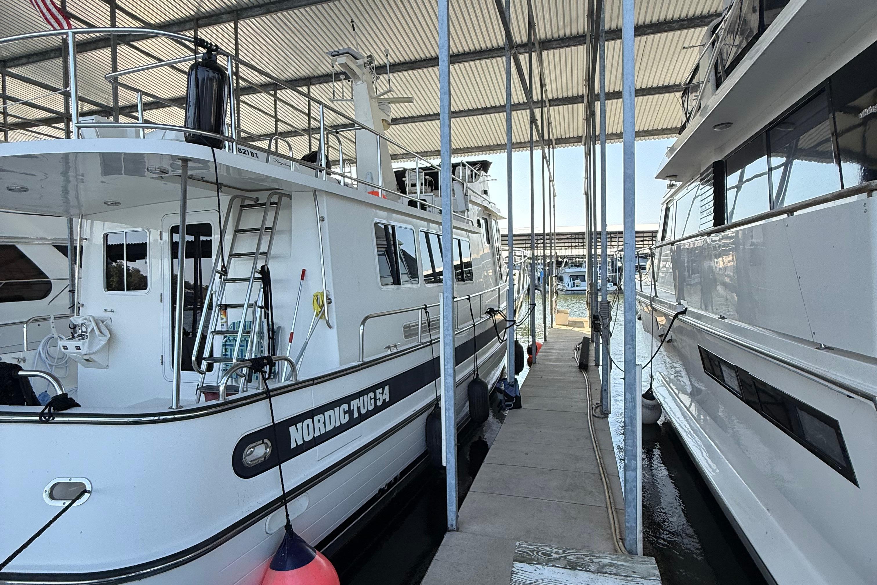 2007 Nordic Tug 54 docked in a marina, side view under covered shelter.