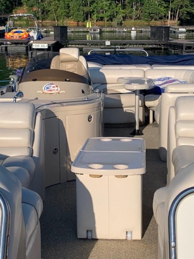 2007 Crest Savannah pontoon boat with beige seating and table on calm water.