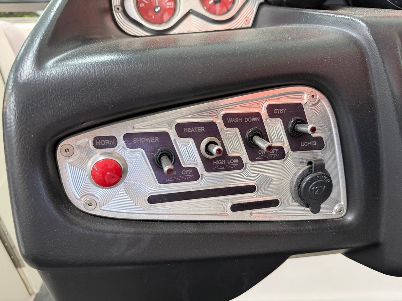 Control panel of a 2006 MasterCraft X30 with various switches and a 12V outlet.