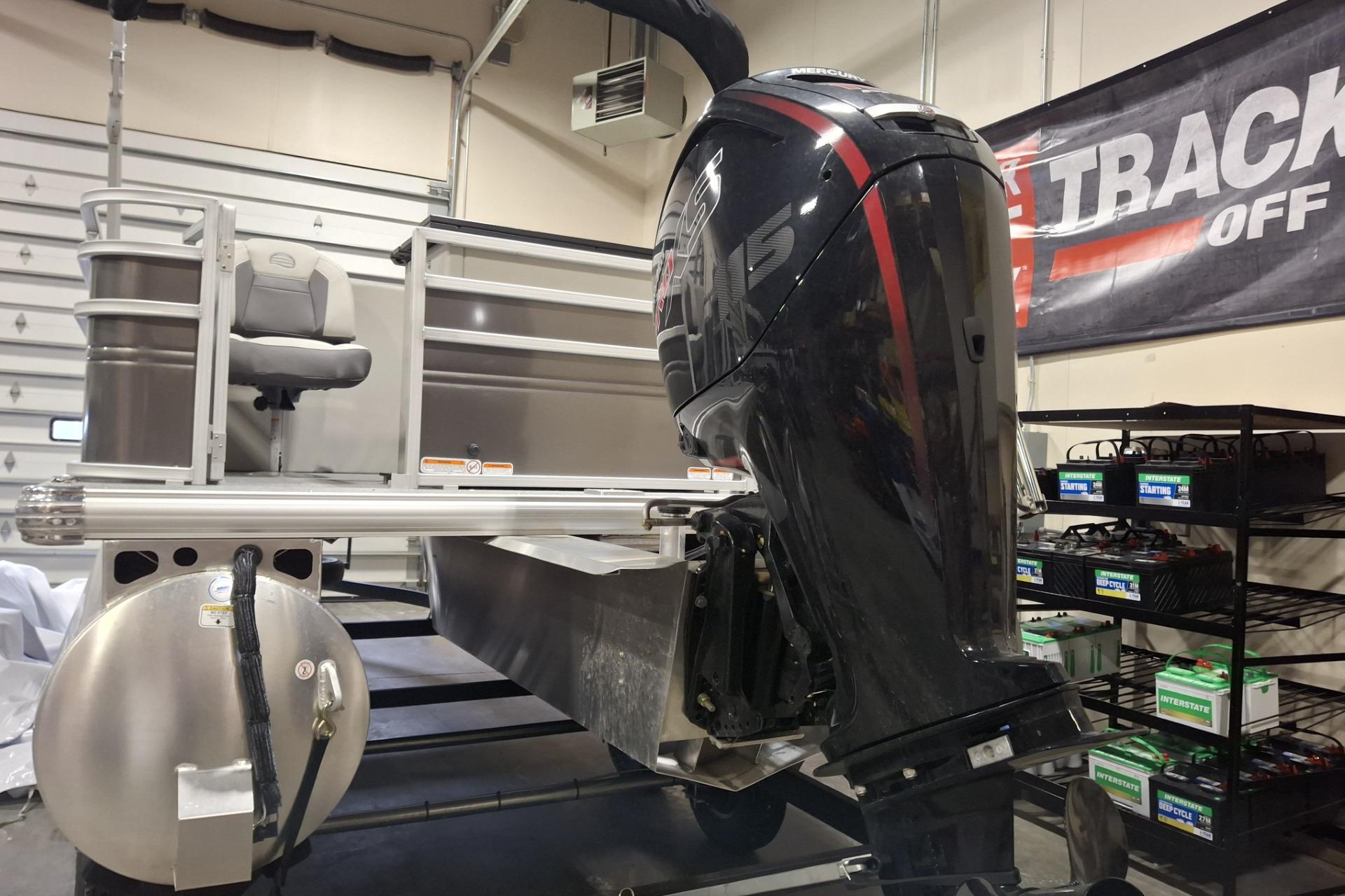 2026 Sun Tracker Party Barge 20 DLX pontoon boat with outboard motor in a garage.