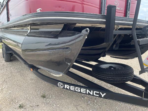 2023 Regency 250DL3 pontoon boat on trailer, close-up of hull and logo.