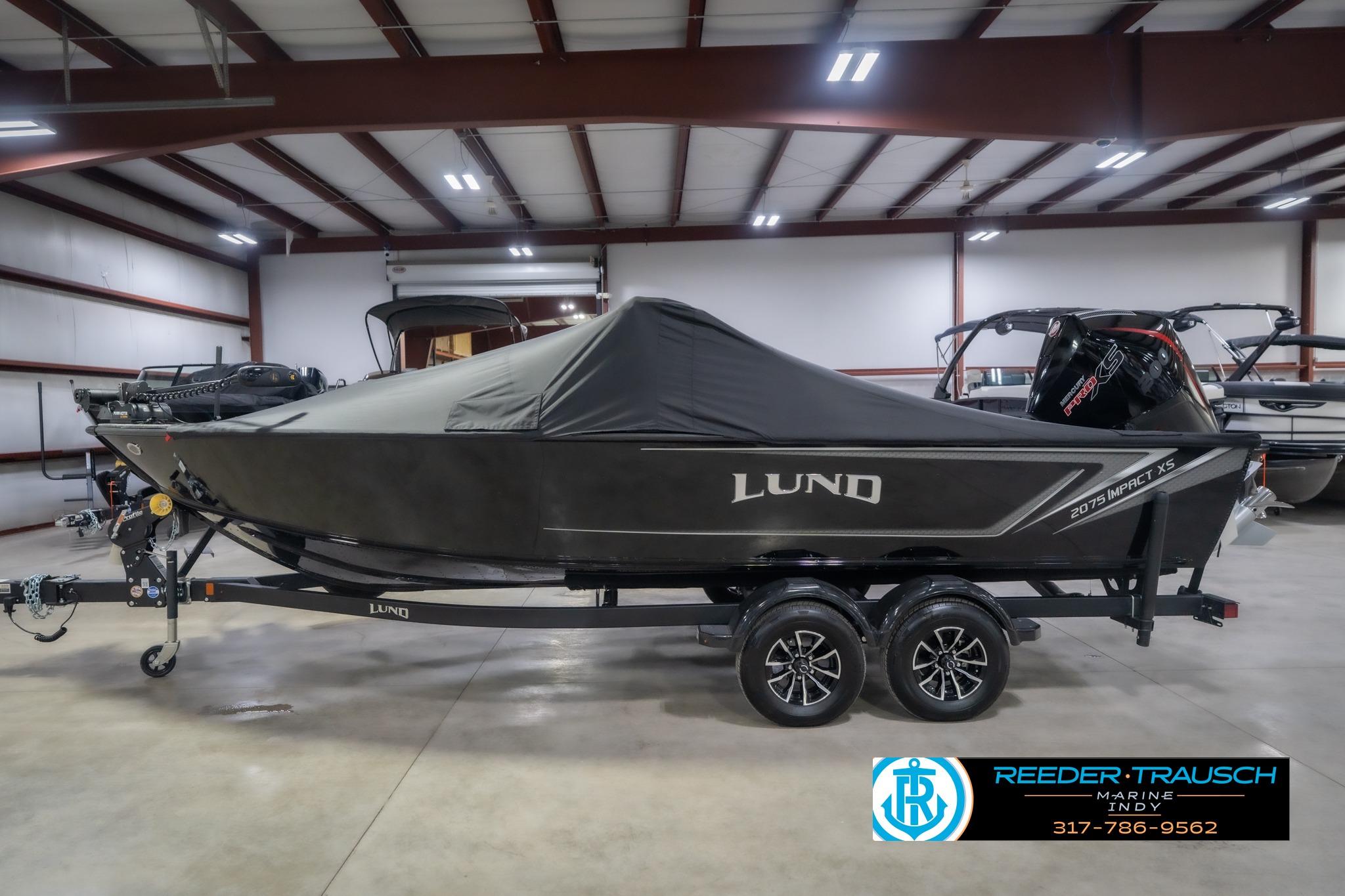 2026 Lund 2075 Impact XS boat with cover in a showroom, on a trailer.