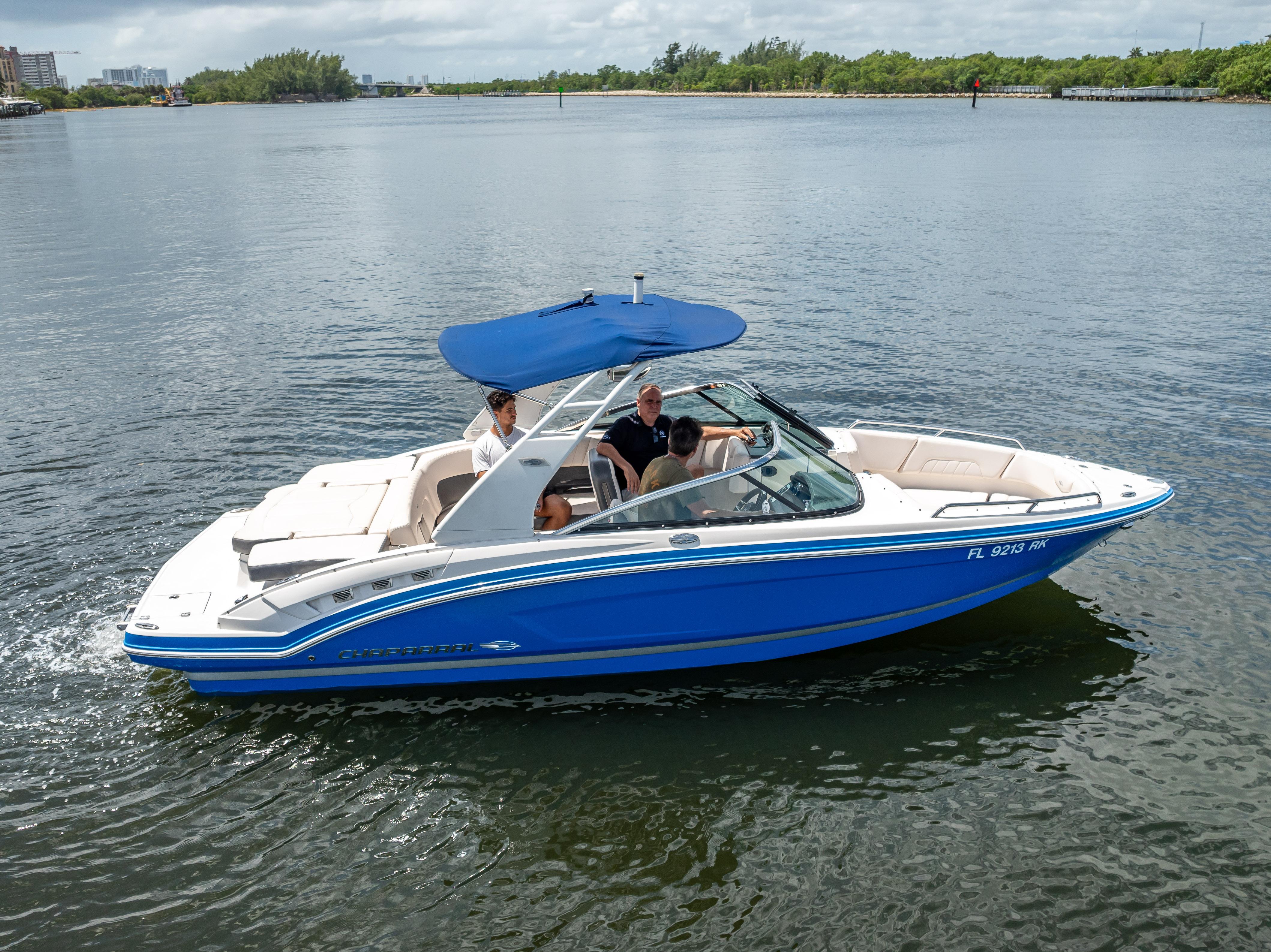 2017 Chaparral 227 SSX boat with blue canopy cruising on calm water.