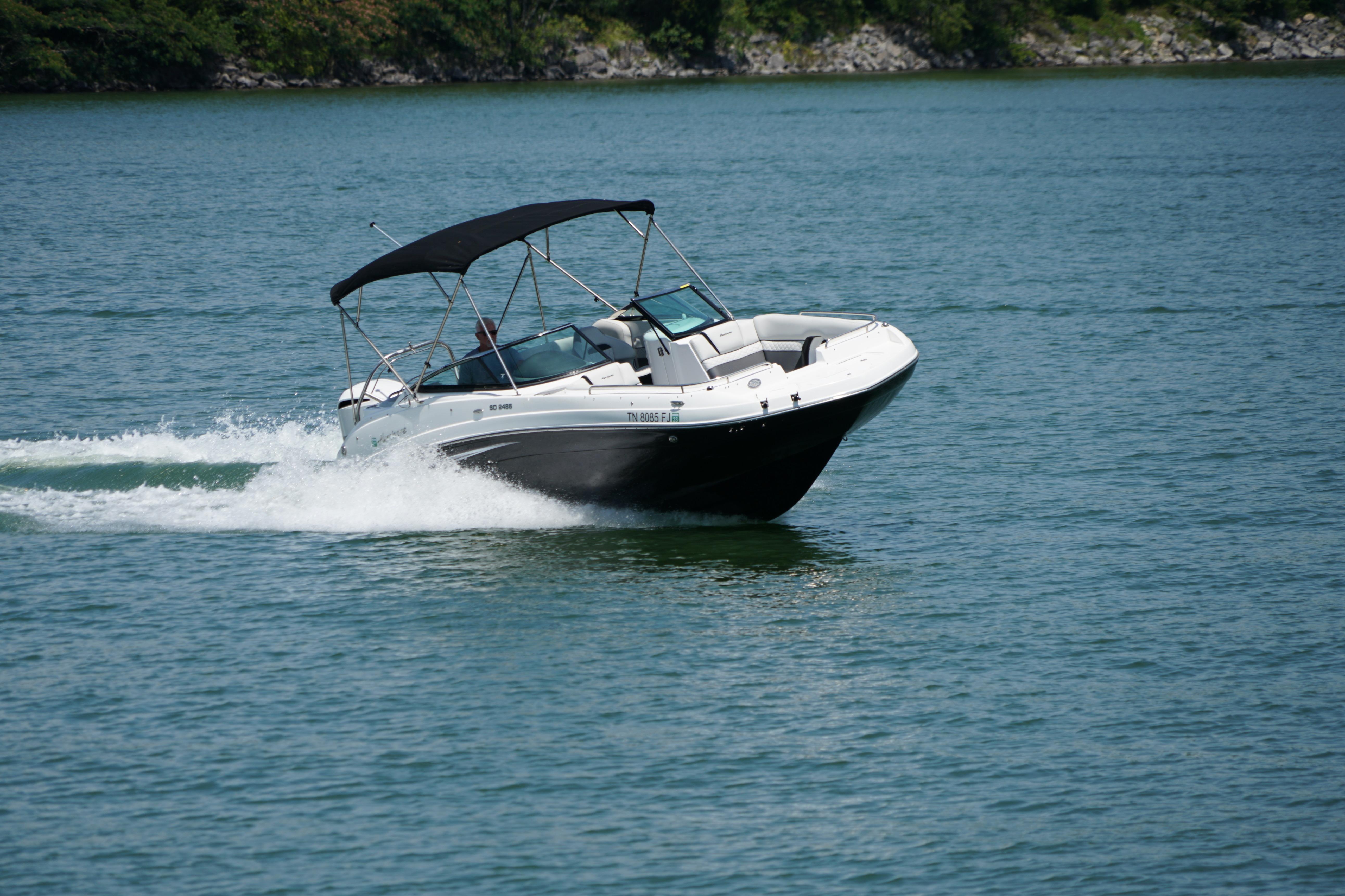 2020 Hurricane SunDeck 2486 OB boat cruising on a serene lake.