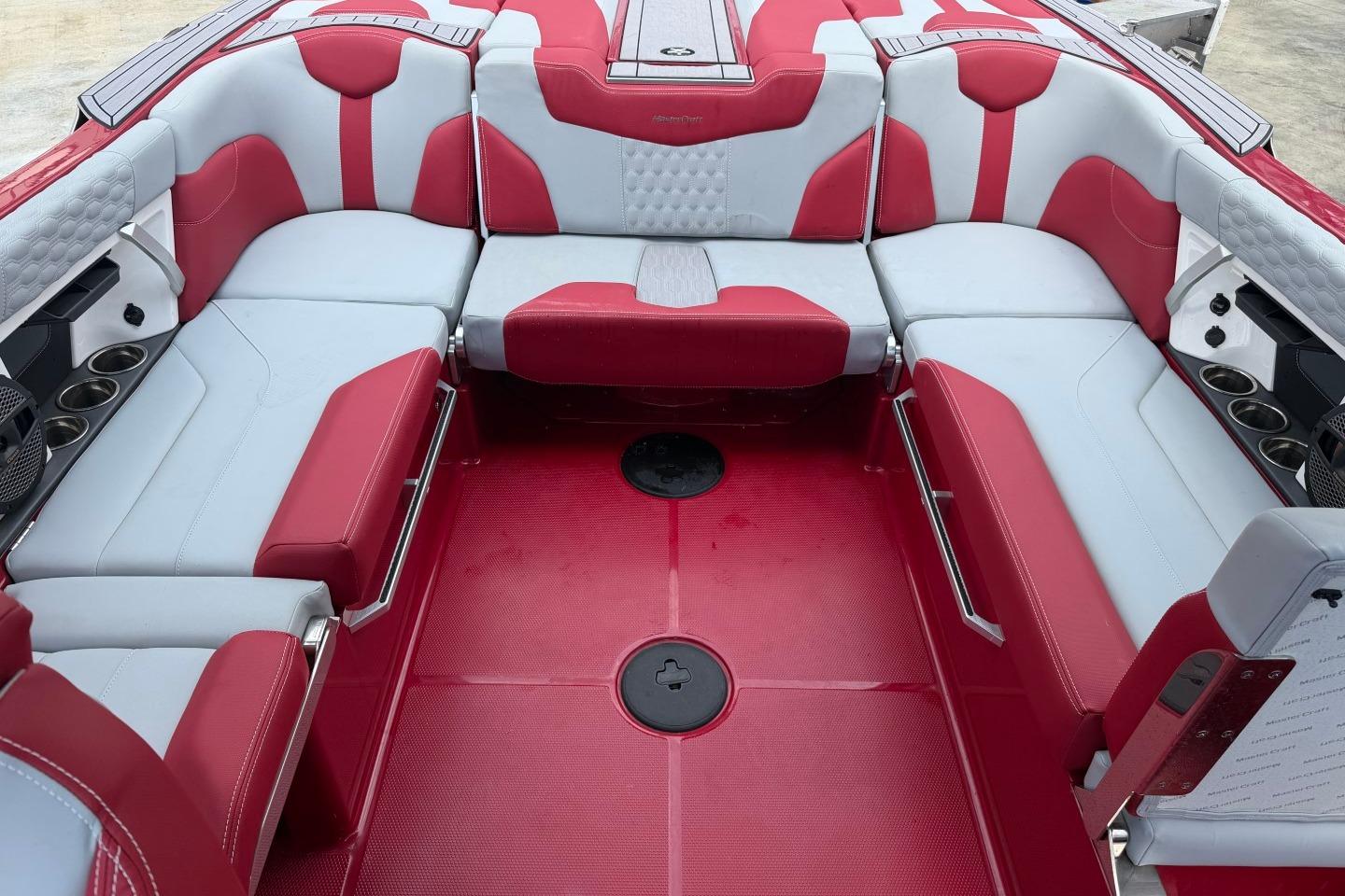 2023 MasterCraft X24 boat interior with red and white seating, cup holders, and modern design.