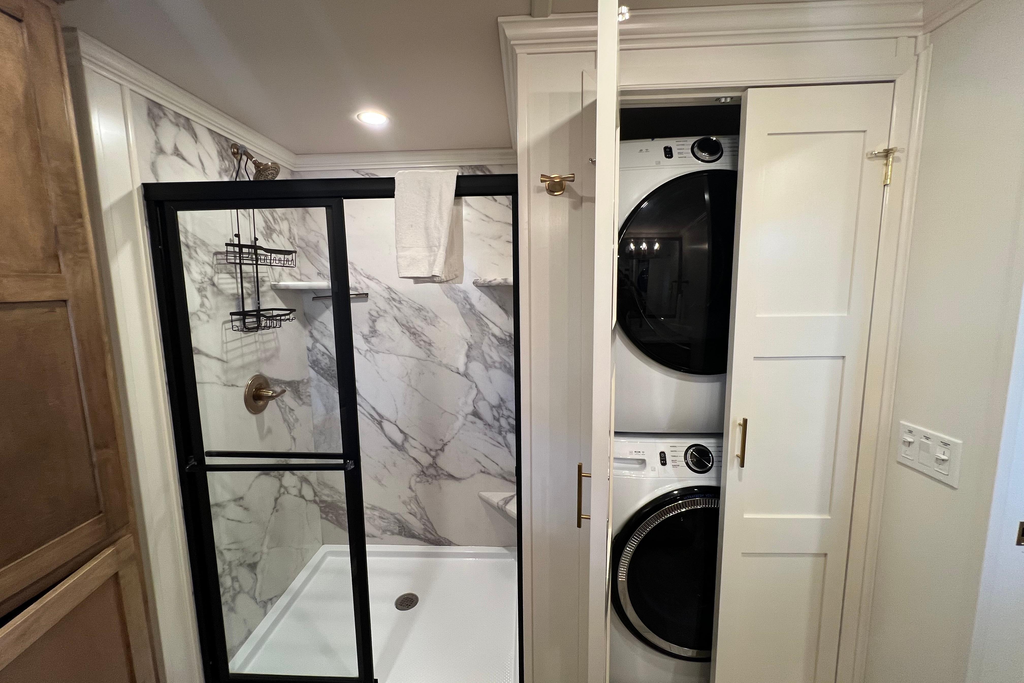 Modern bathroom with marble shower and stacked washer-dryer in Sumerset Excellence Multiple Shares 2025.