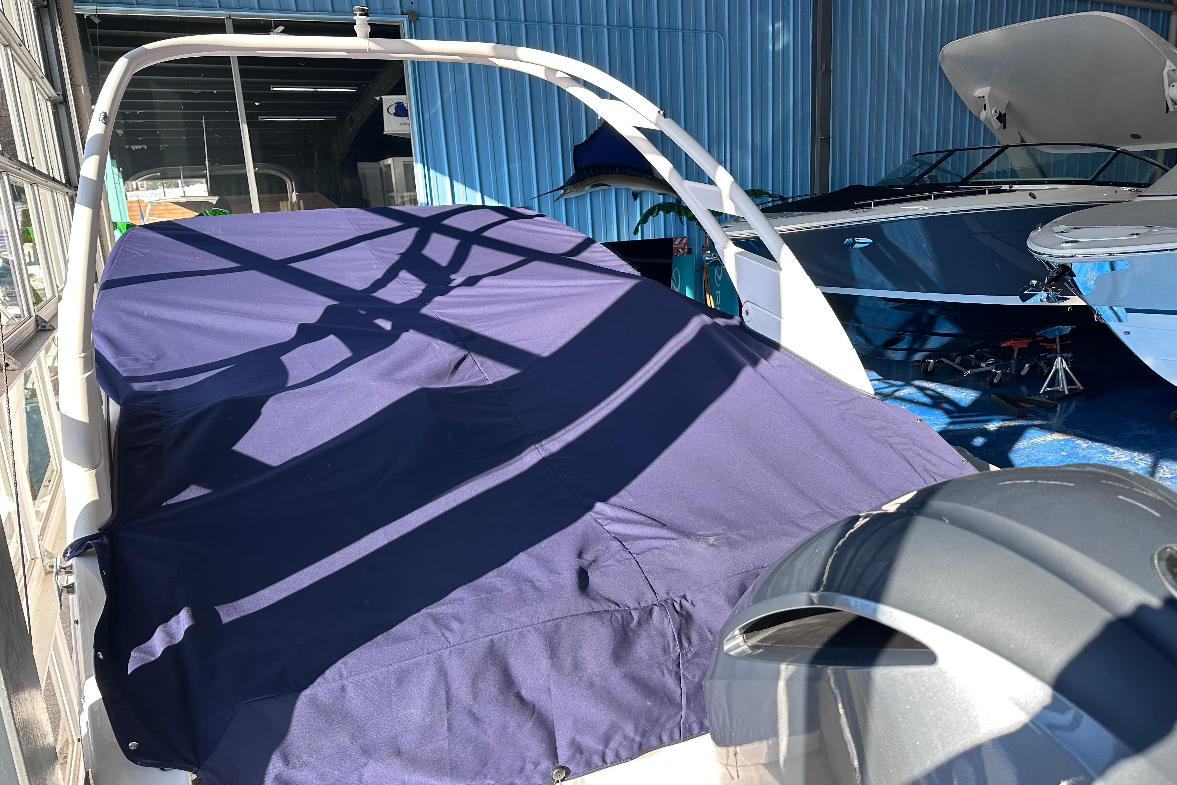 Covered 2026 Regal LX4 boat in storage, with blue tarp and surrounding boats.
