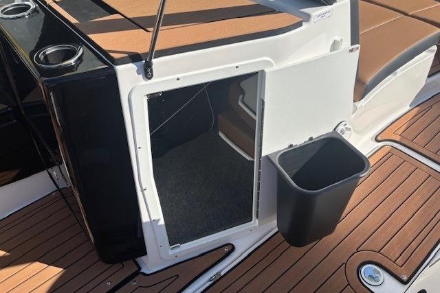 2026 Yamaha Boats 222SE interior storage compartment with open door and trash bin on deck.
