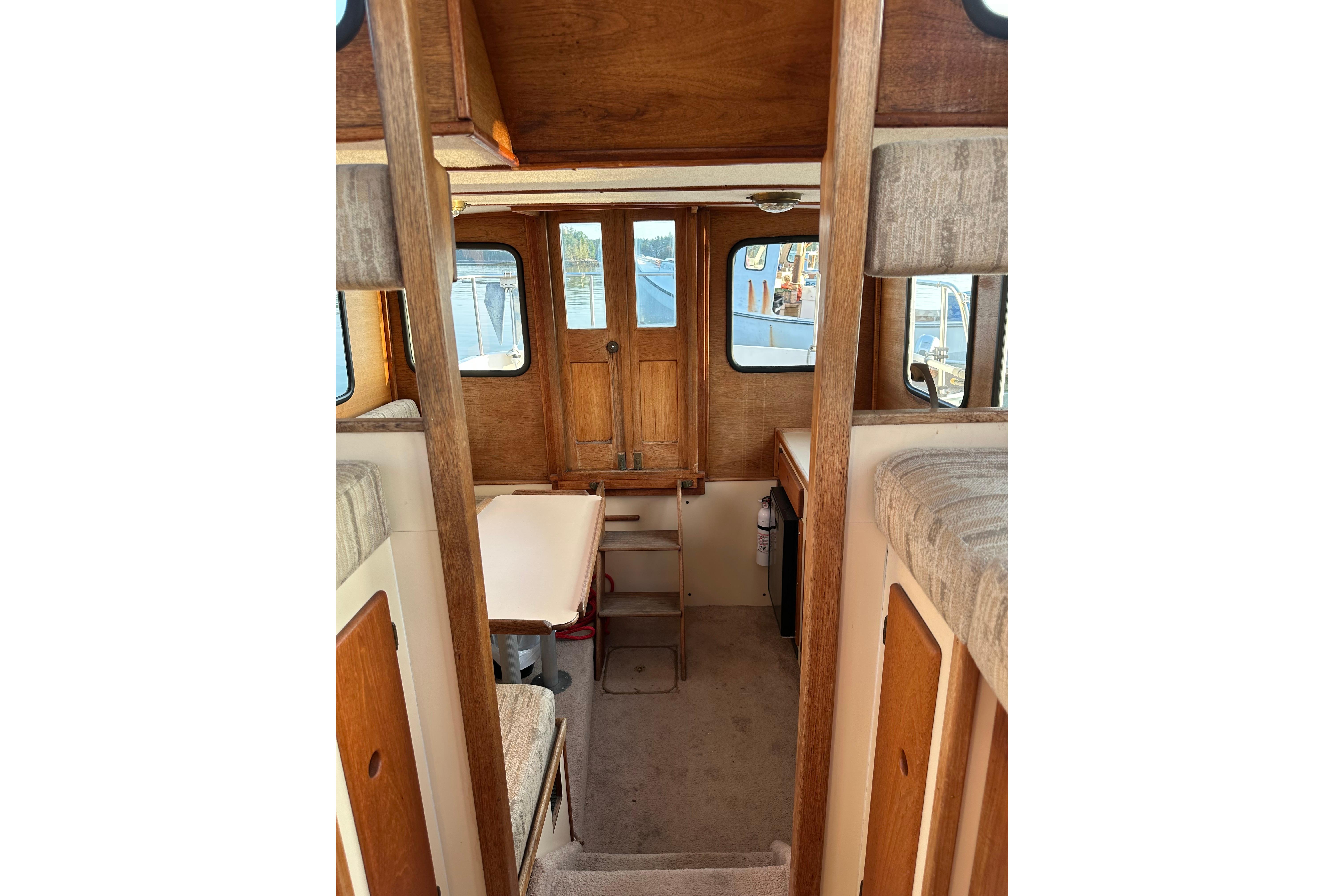Interior of a 1985 Nordic Tug 26, featuring wood paneling and compact seating area.