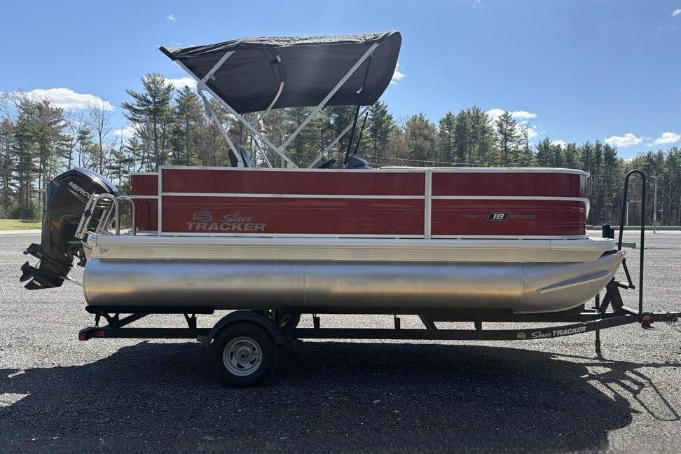 2026 Sun Tracker Party Barge 18 DLX pontoon boat on trailer, parked outdoors.