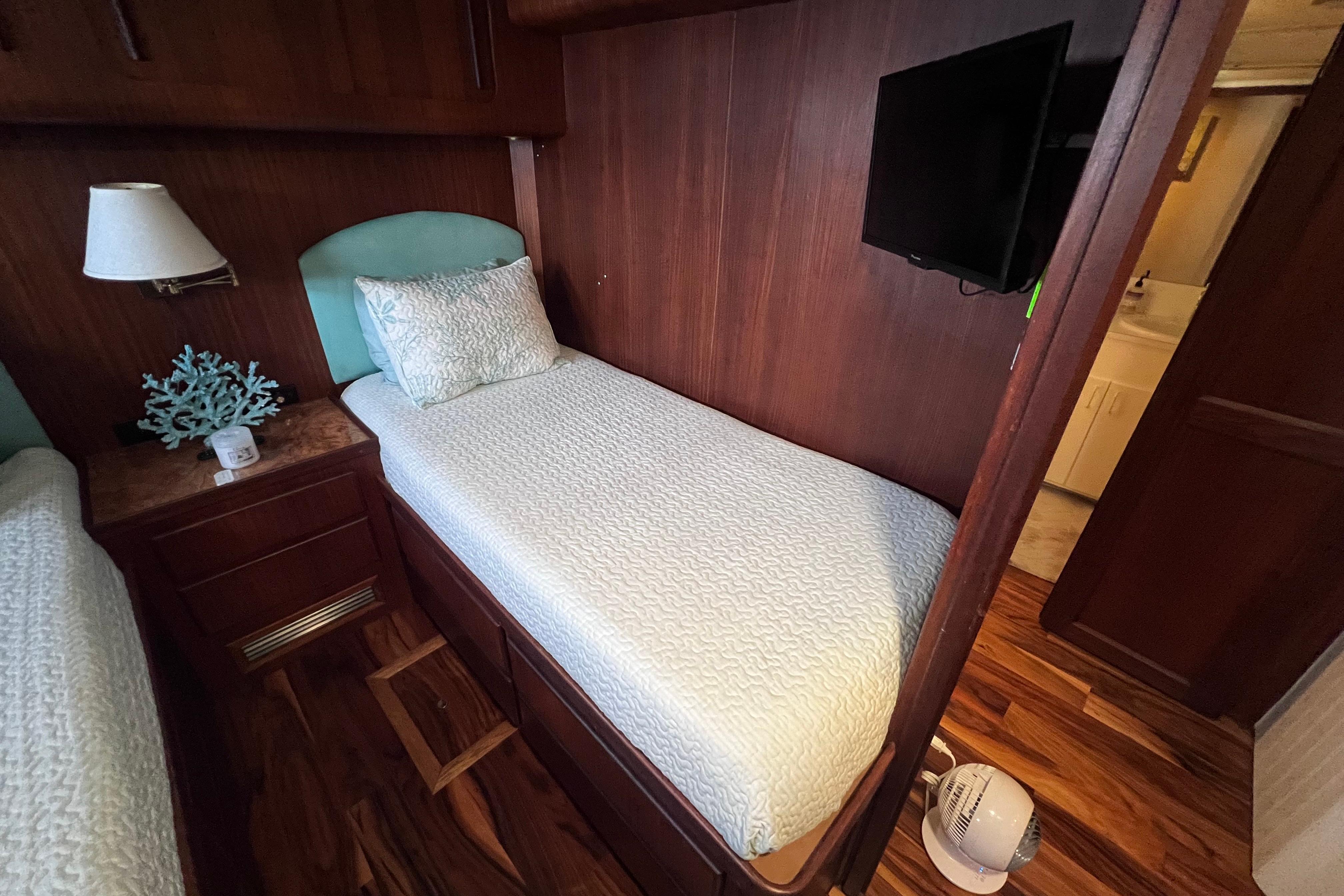 Cozy cabin interior of 1987 Hatteras 70 Cockpit Motor Yacht with twin beds and TV.