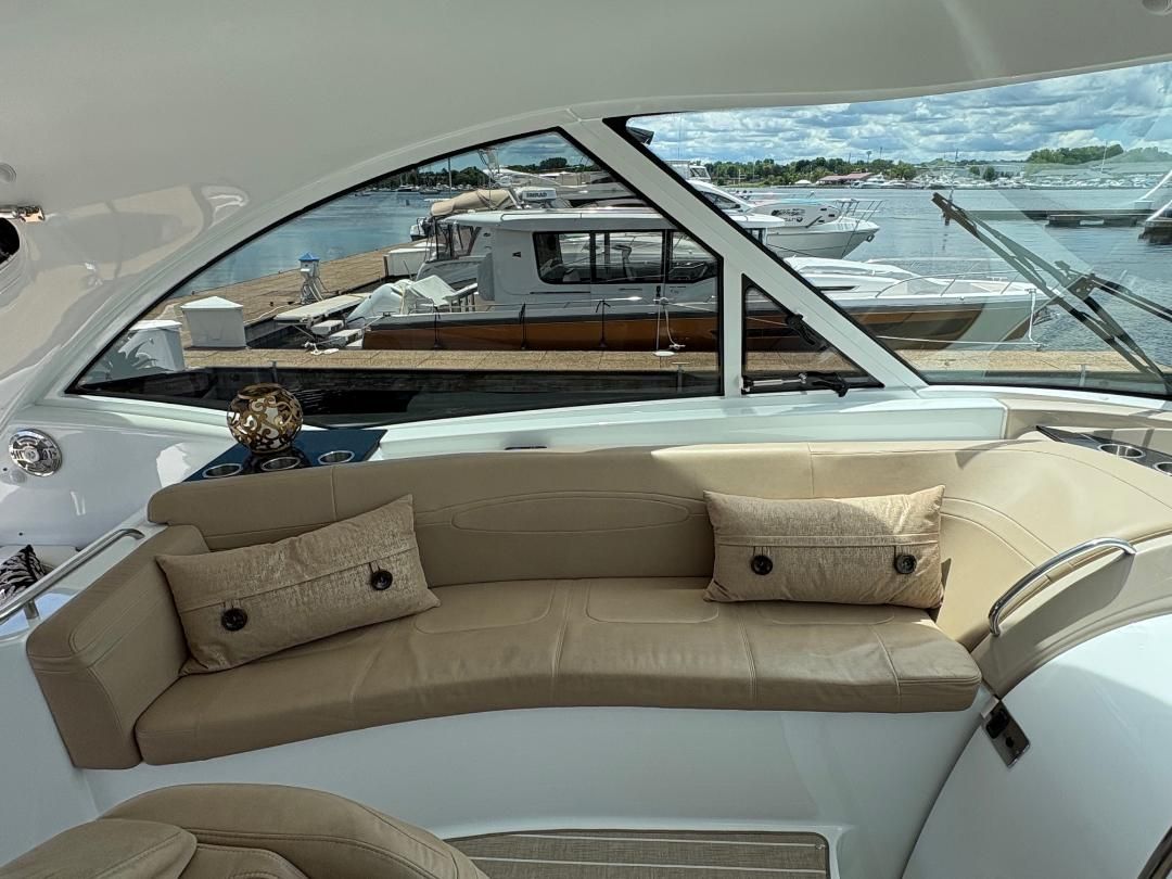 The image shows the interior of a 2011 Formula 45 with a beige leather couch and cushions. Boats are visible docked in the background.