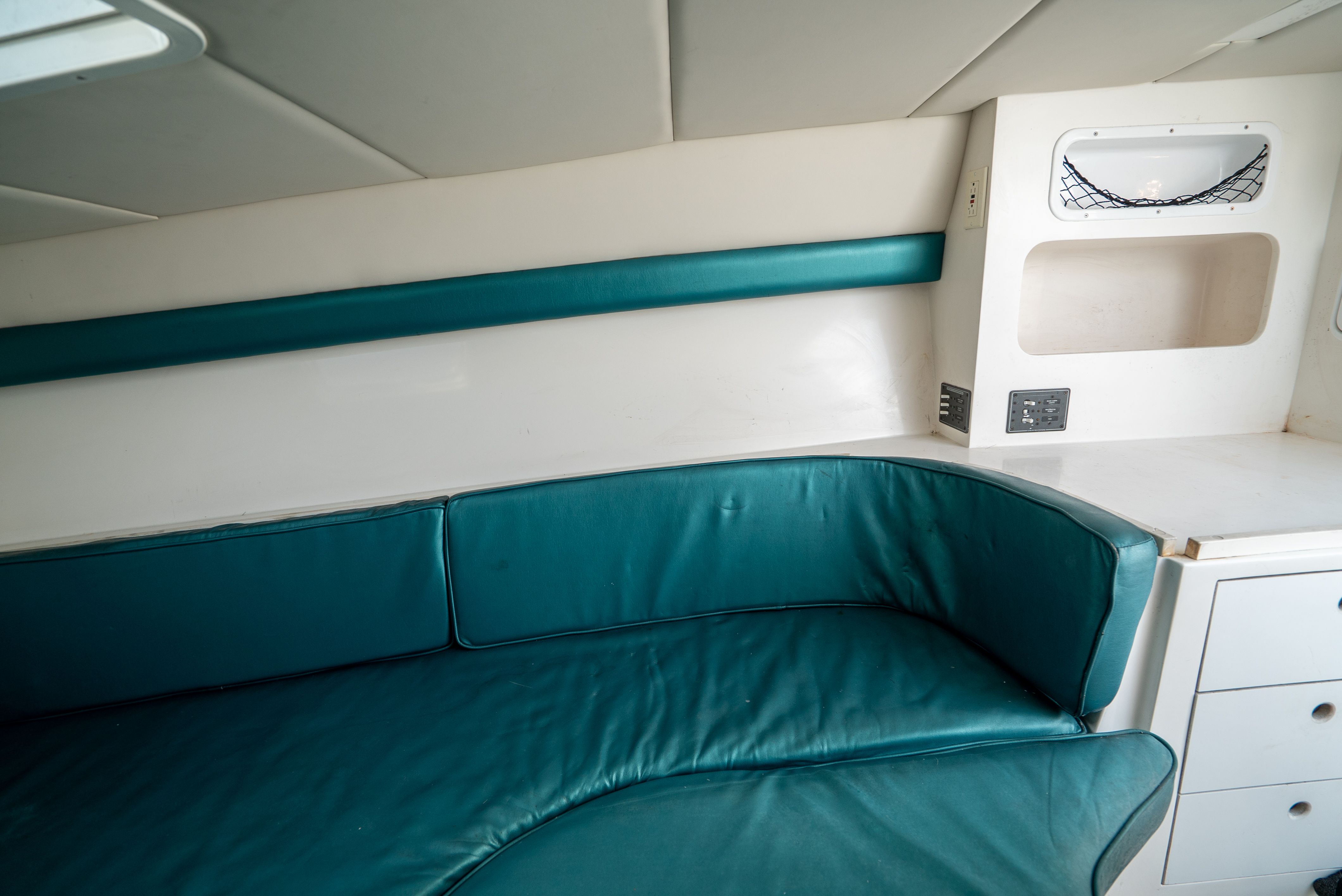 Interior of a yacht with green upholstery and white walls.