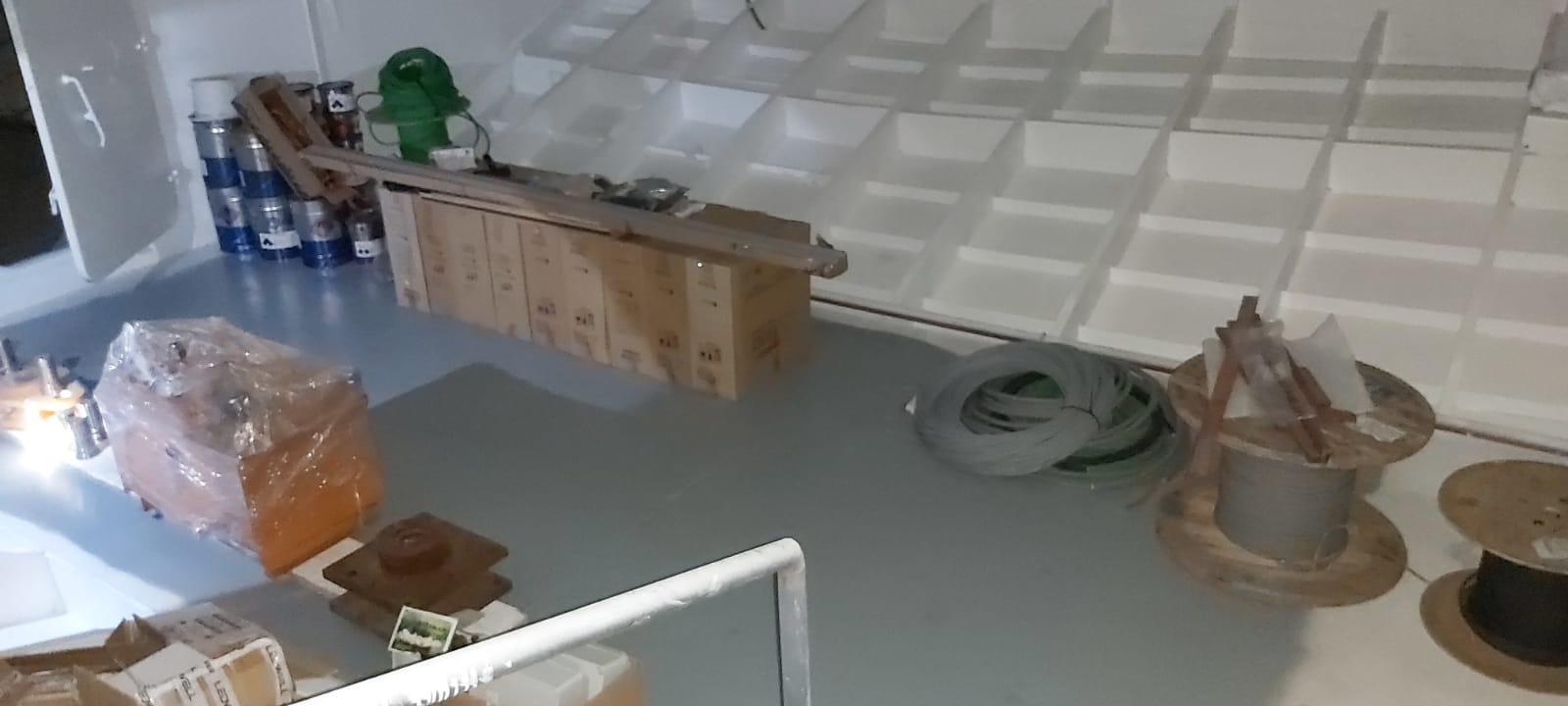 Storage area with various supplies, including cables, boxes, and paint cans, inside a Custom 42M, 2024 model.