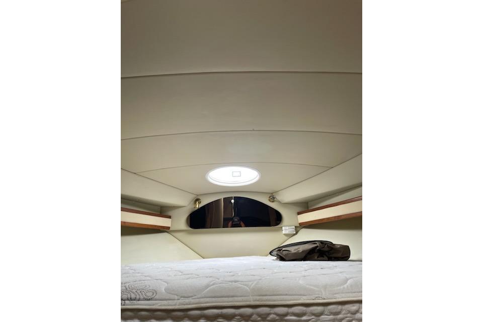 Interior cabin of 2002 Cruisers Yachts 3372 Express, featuring a cozy bed and porthole.