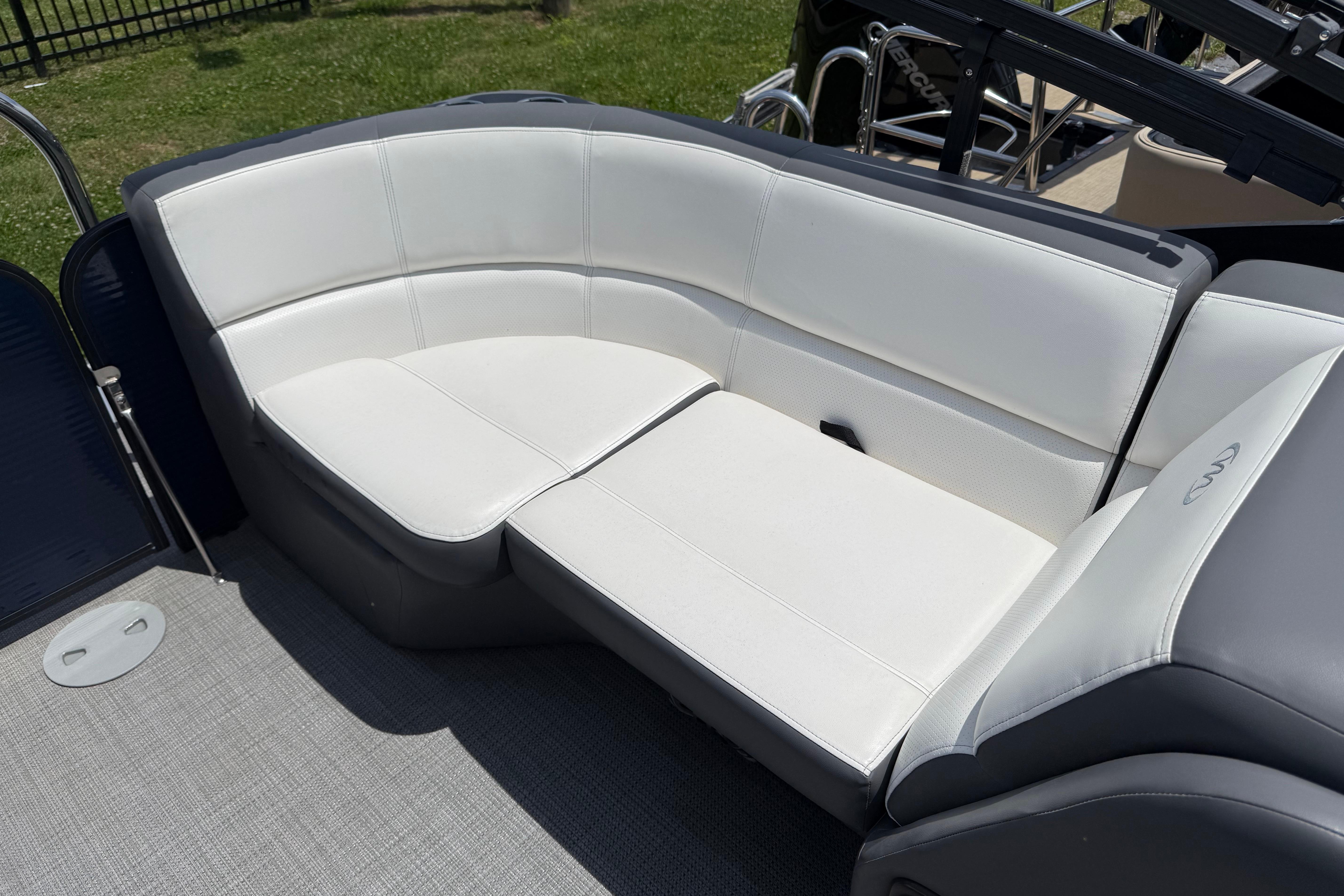 2022 Manitou Aurora LE boat with white cushioned seating on deck.