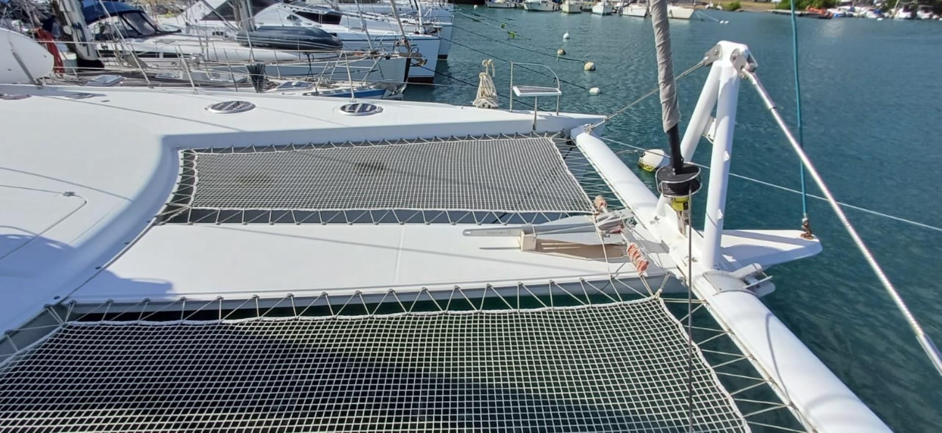 Catamaran deck of 2008 Fountaine Pajot Eleuthera 60 with netting, docked in marina.