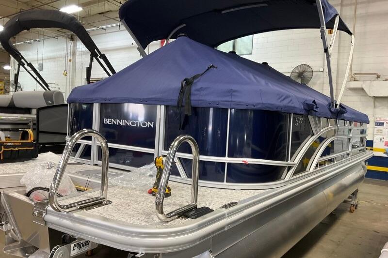 2026 Bennington 23 SSRSF pontoon boat with blue cover in a warehouse setting.