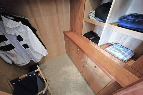 Walk-in closet on 2005 Sunseeker Manhattan 66 yacht with wooden shelves and hanging space.