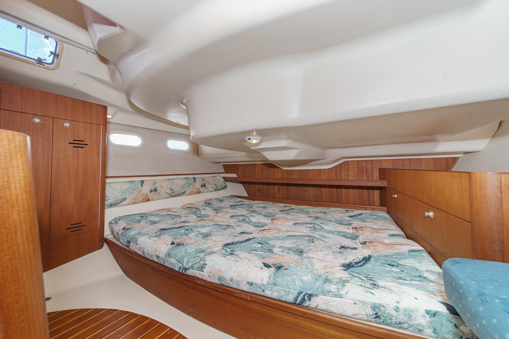 Cozy cabin interior of a 1996 Hunter 376 sailboat with wood accents and patterned bedding.