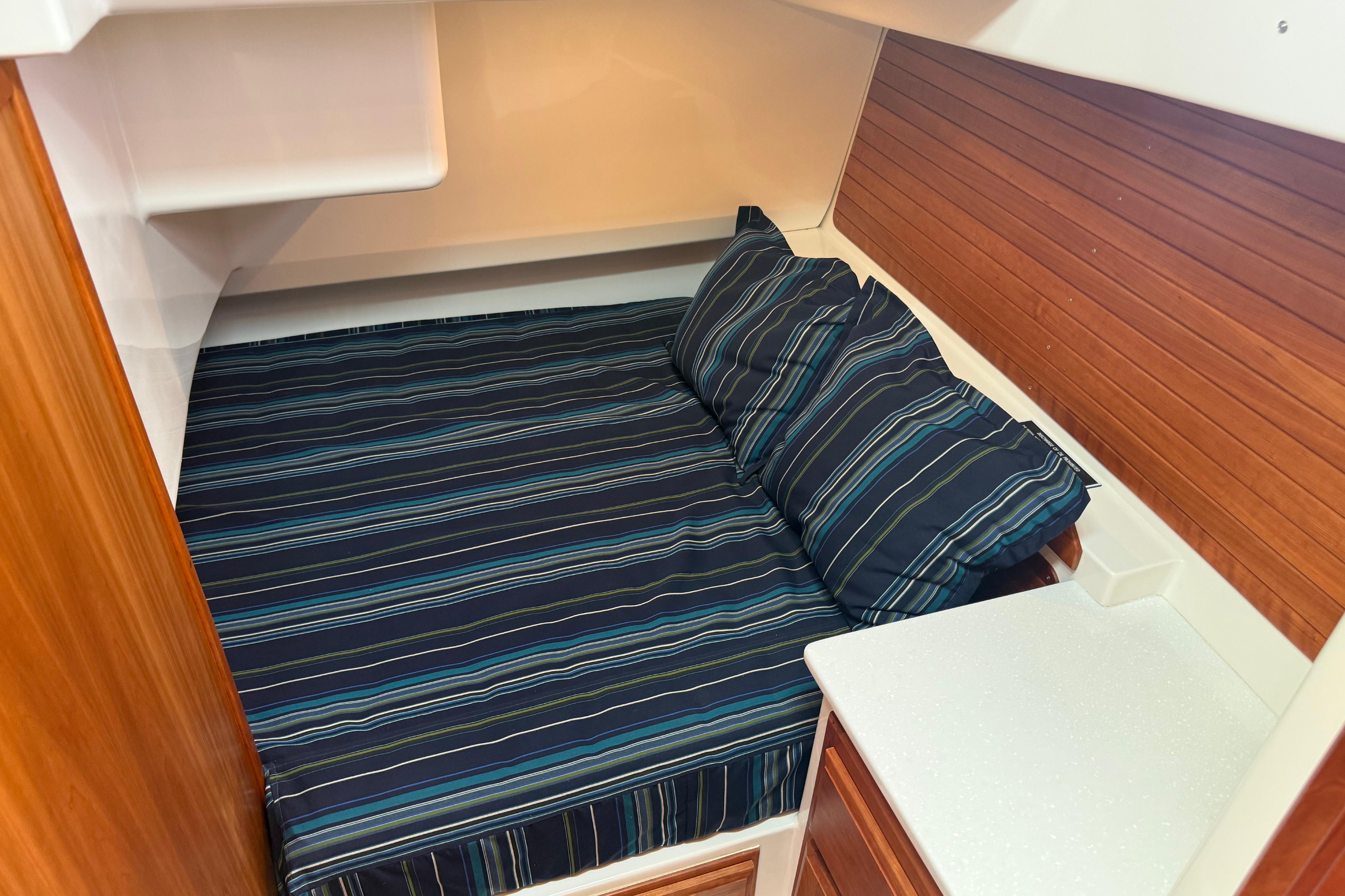 Cozy cabin interior of 2018 Back Cove 41 with striped bedding and wooden accents.