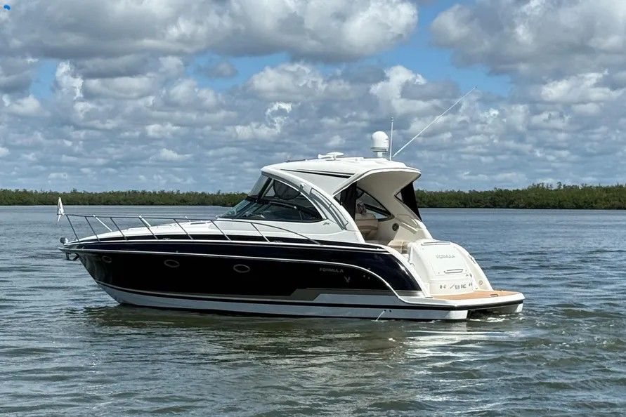 A sleek motorboat with a curved design on calm water under a cloudy sky.