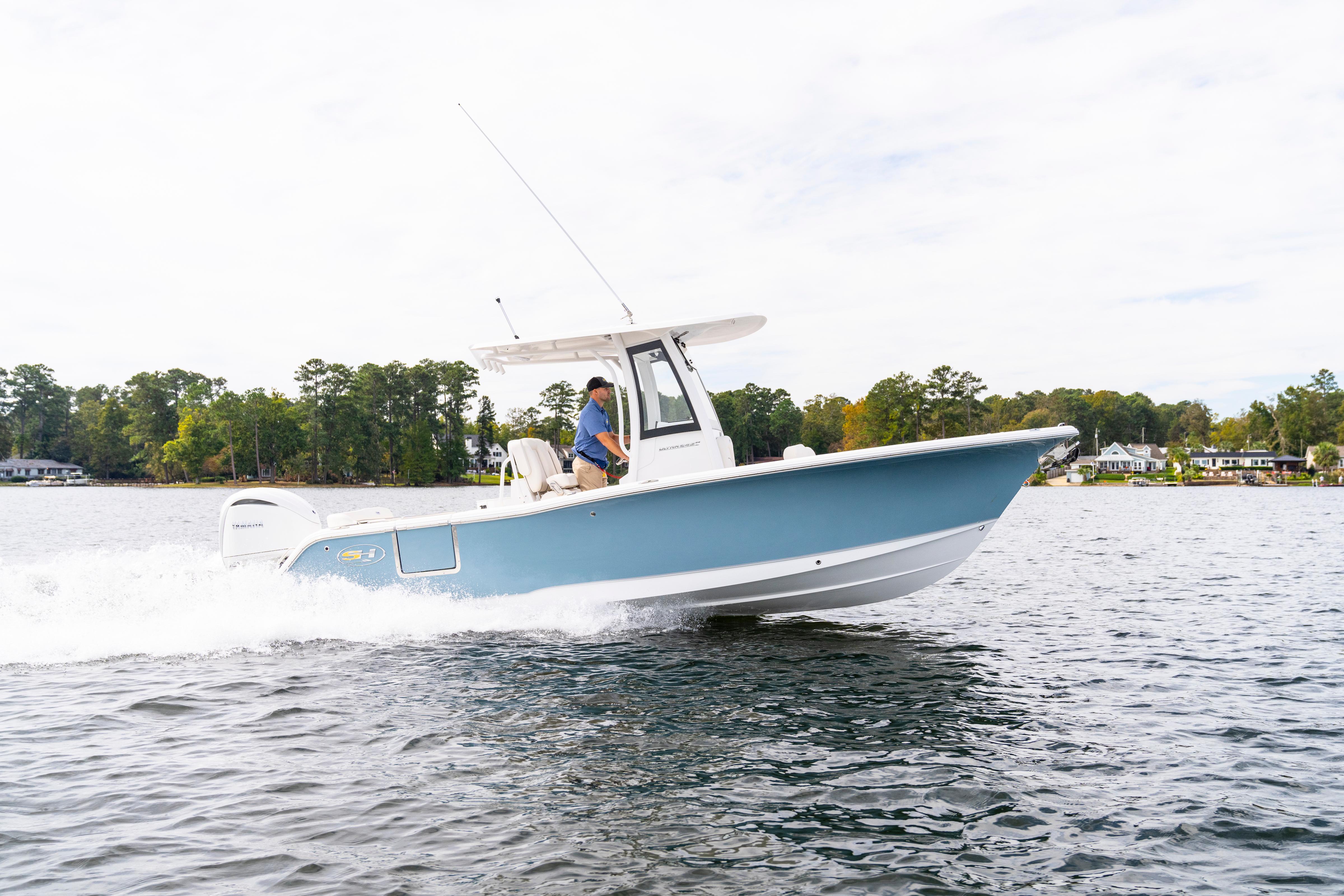 2026 Sea Hunt Ultra 245 SE boat cruising on a lake with trees in the background.