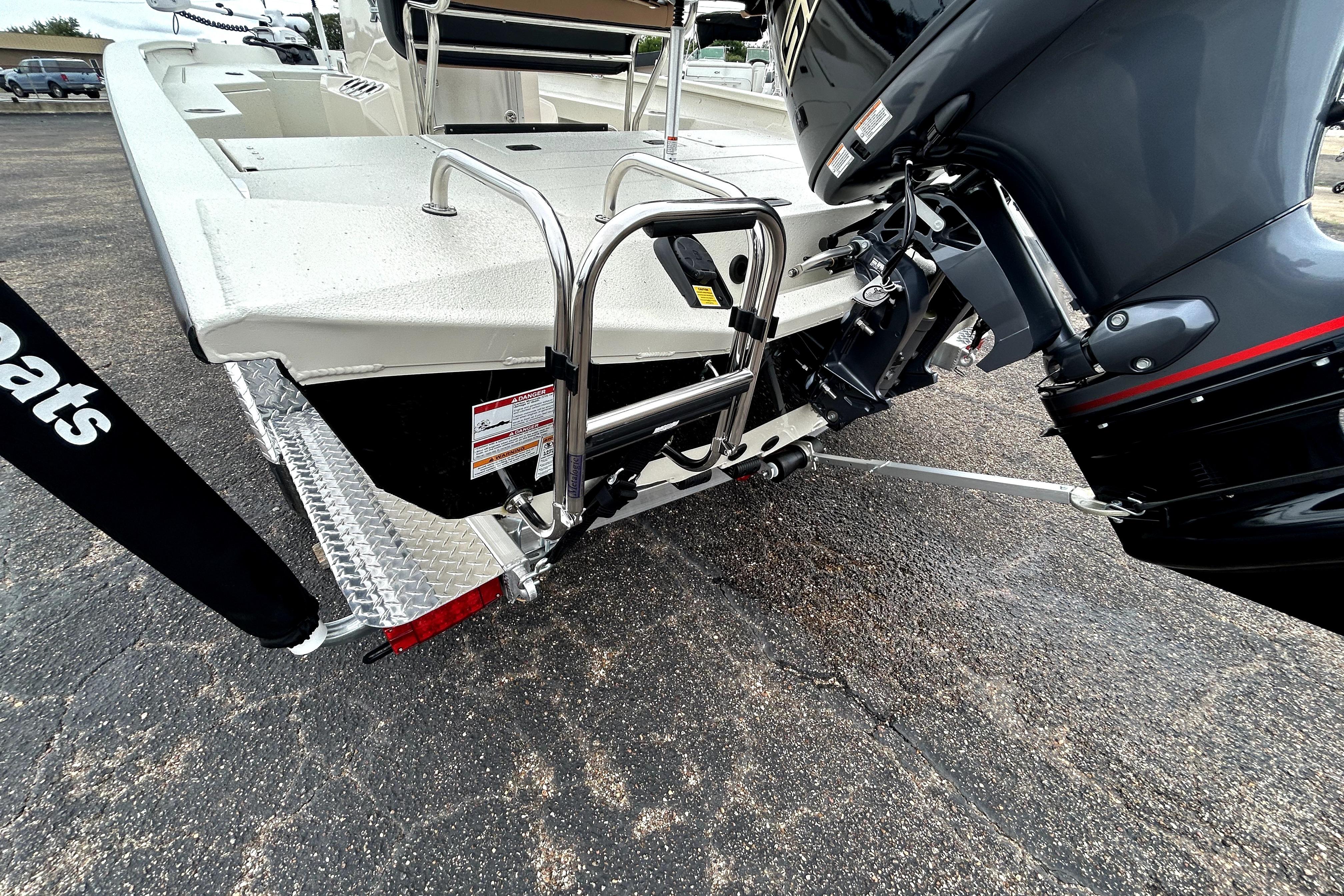 2026 Xpress H20B Bay boat rear view with motor and ladder on pavement.